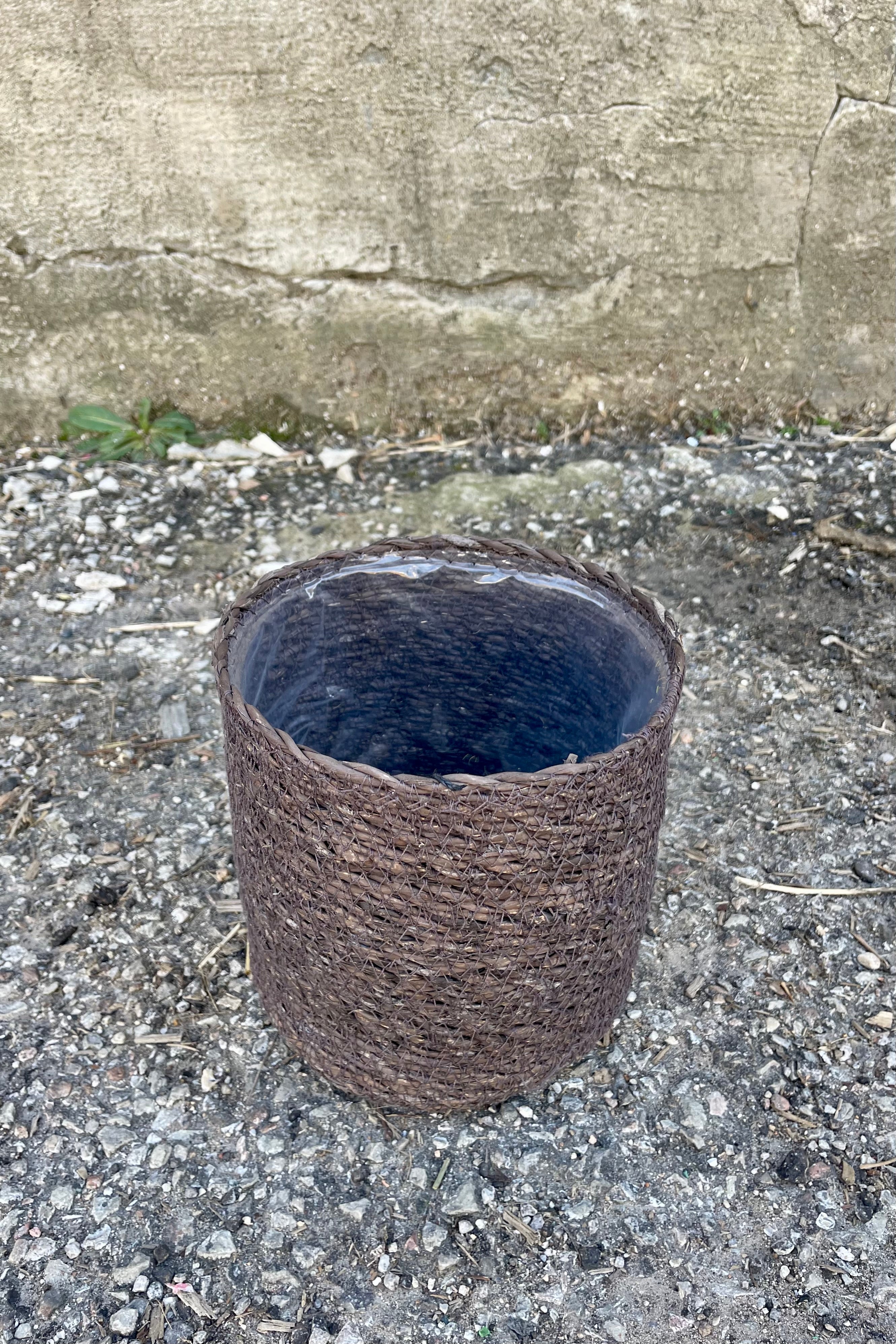 Photo from above of black seagrass basket with liner against a cement wall.