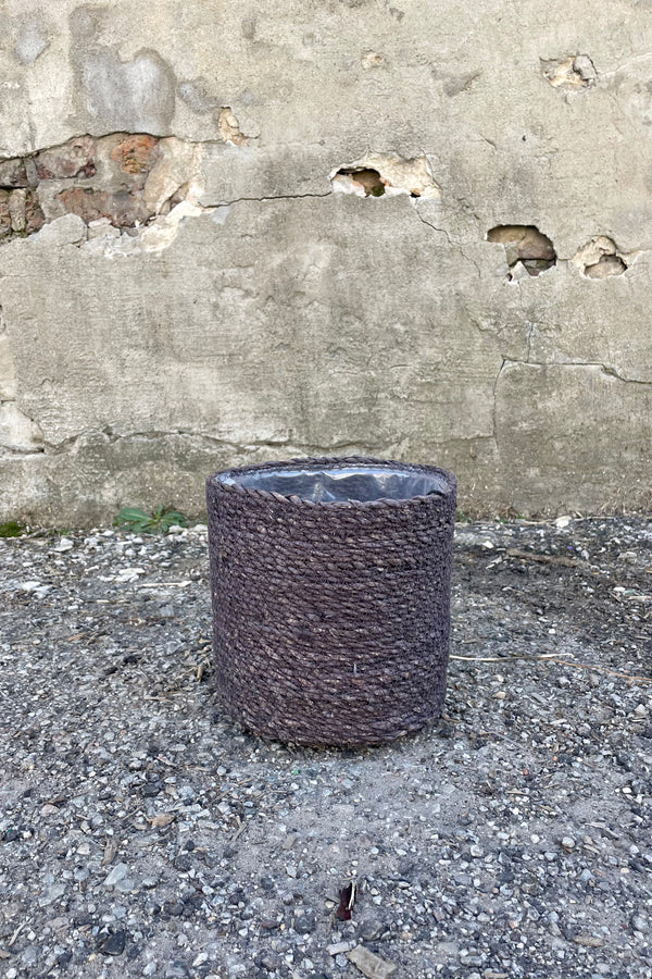 Photo of black seagrass basket with liner against a cement wall.