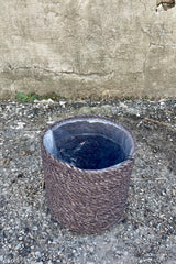 Photo from above of black seagrass basket with liner against a cement wall.