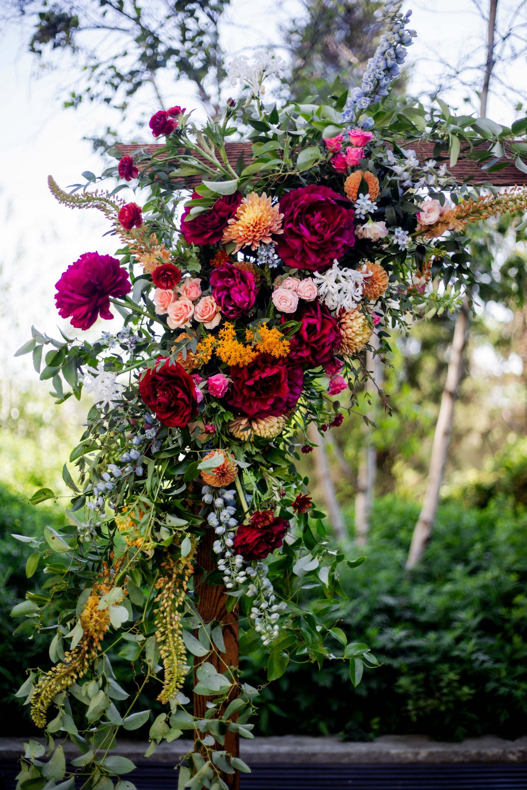 Part of a wedding arch designed by Sprout Home composed of a burgundy and yellow color theme at the Greenhouse Loft @laynedixonphoto