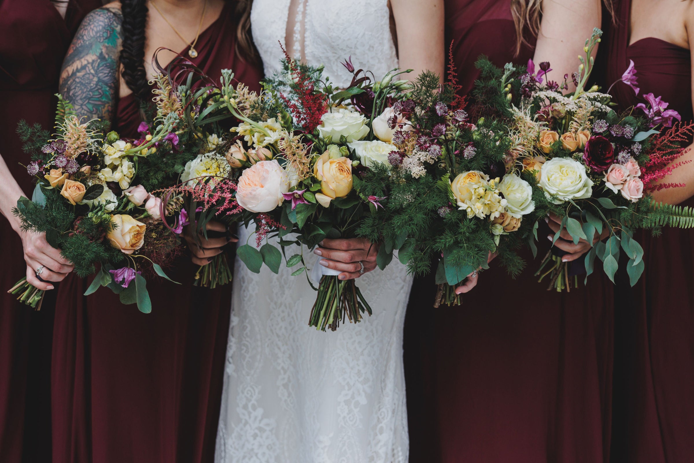 Bridal and bridesmaid bouquets by Sprout Home being held in hand together. Photograph by Angela Renee Photography