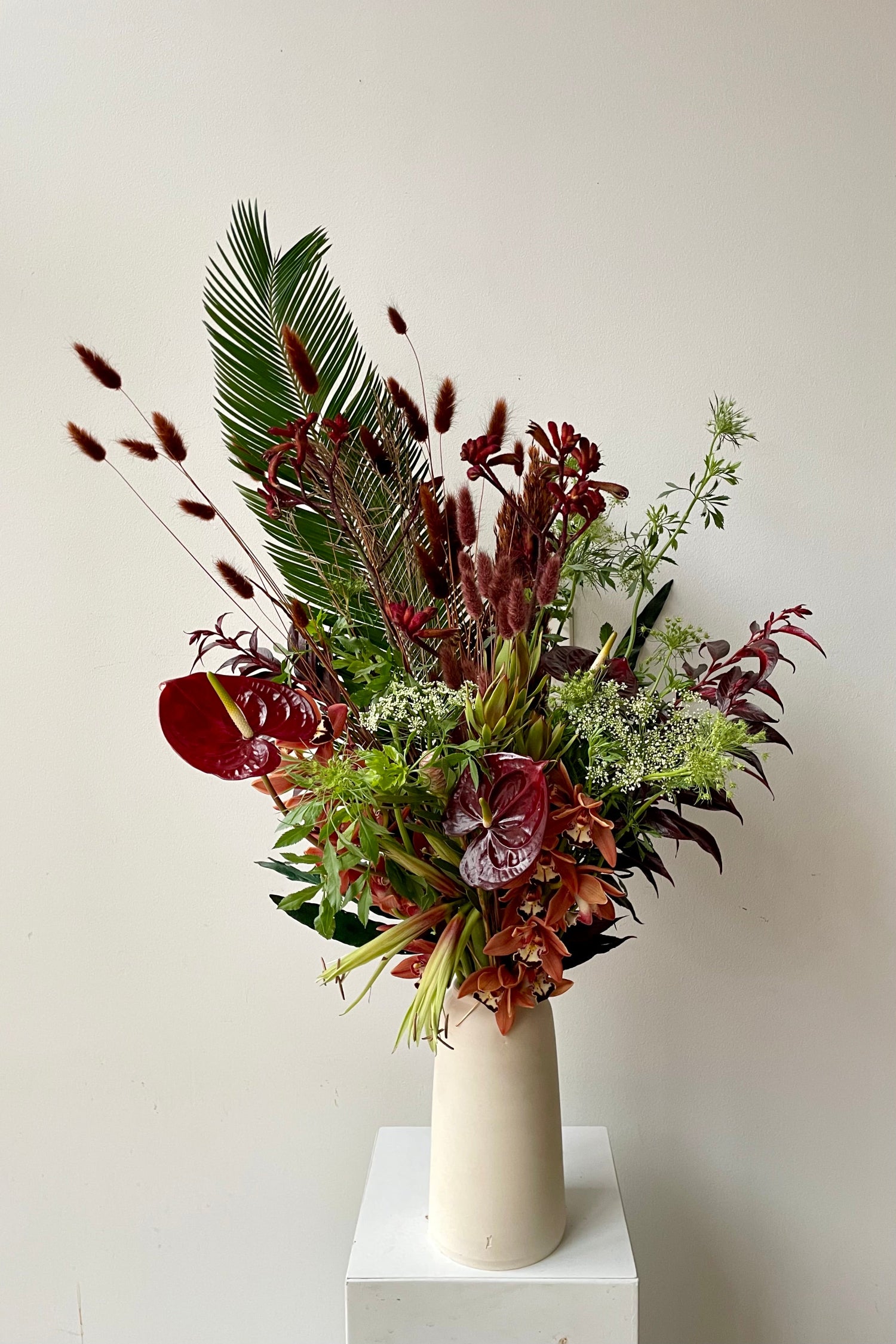 A sexy tropical floral arrangement by Sprout Home featuring preserved lagers, anthurium, orchids and palm in a L'Impatience vase. Photo by Sprout Home
