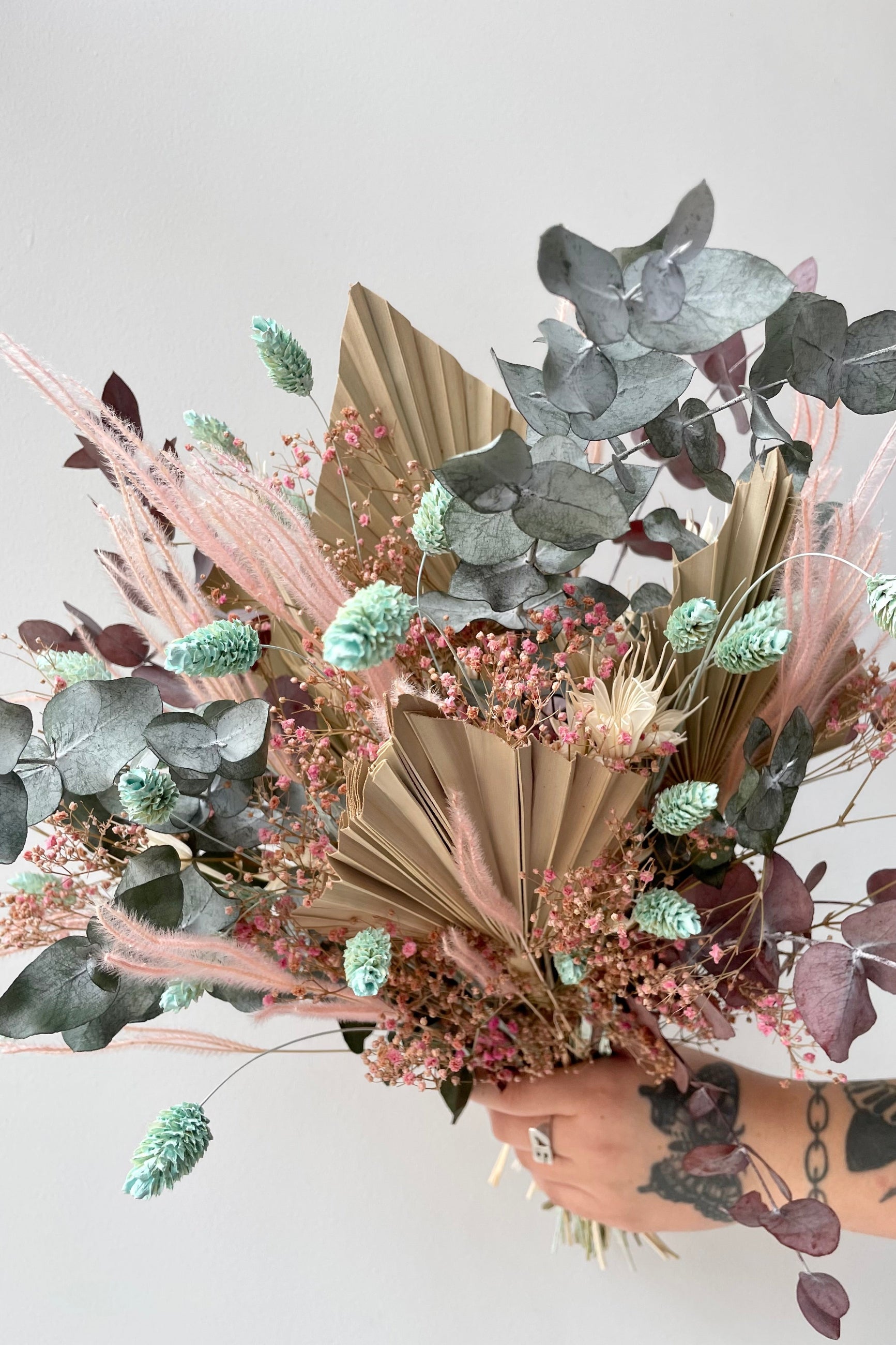'Faerie' arrangement with shades of neutral and pastel created by Sprout Home being held against a white wall. ©Sprout Home #size_$125