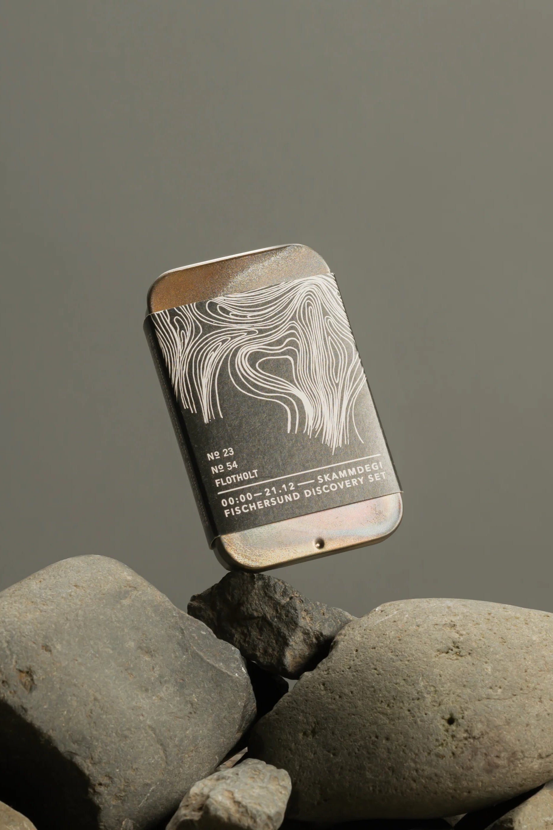 Fischersund's Skammdegi (DARK) Discovery Set resting on rocks showing the front design of the box packaging ©Fischersund