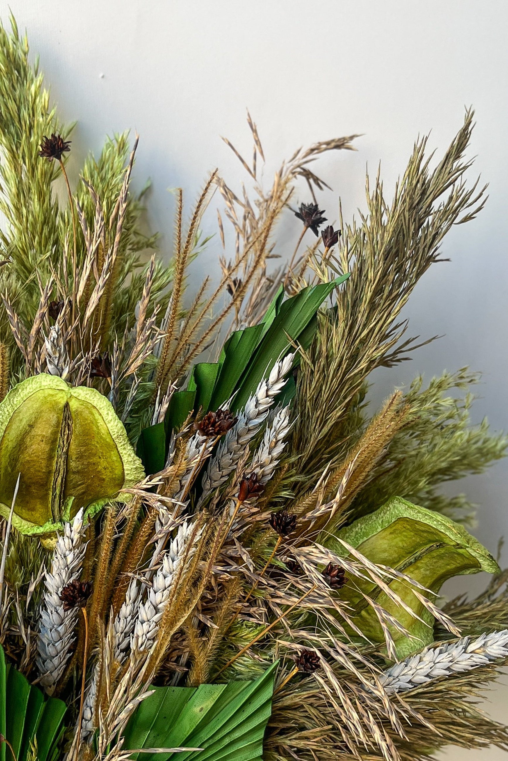 Detail image of the various shades of green and natural earth preserved floral pieces in Sprout Home's custom Floral Borealis dried arrangement ©Sprout Home #size_$200