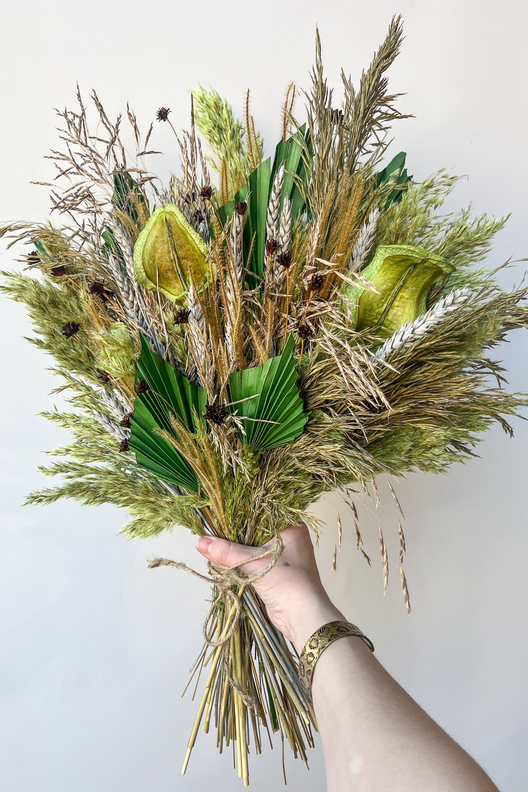 The unique preserved arrangement by Sprout Home 'Flora Borealis' being held in hand showing of the natural shades of green ©Sprout Home #size_$200