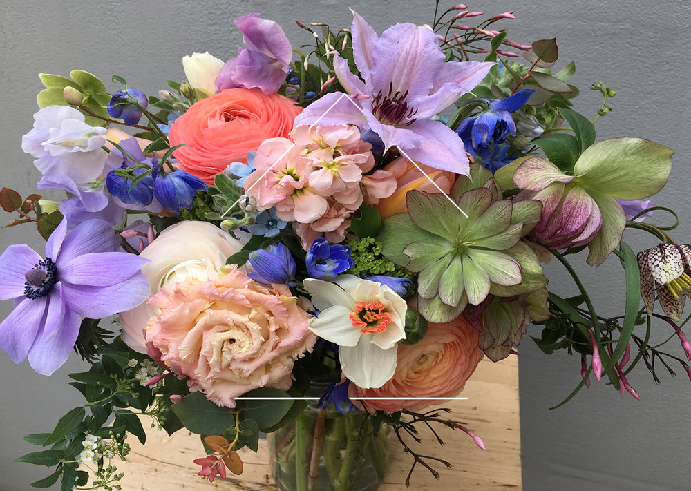 Flower arrangement with purple and peach flowers against grey background