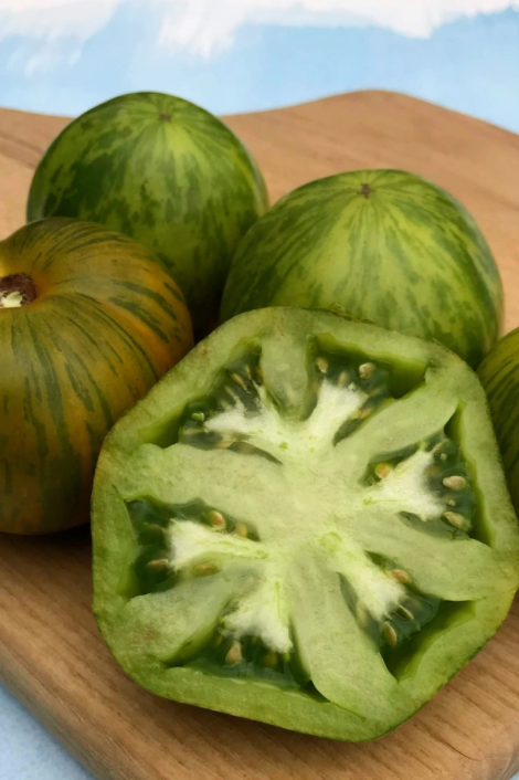 Green Zebra tomatoes whole and sliced on a wood board by Hudson Valley Seeds Company.