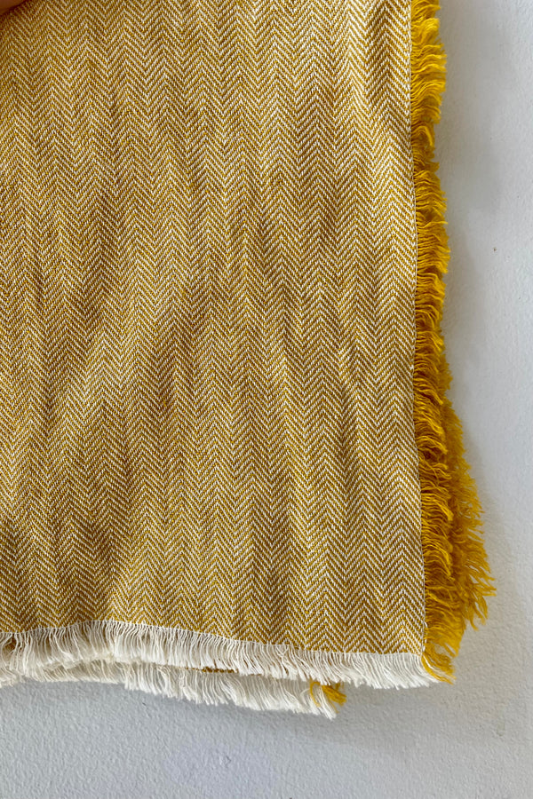 Close detail Photo of a Herrinbone pattern Mustard colored fringed napkin