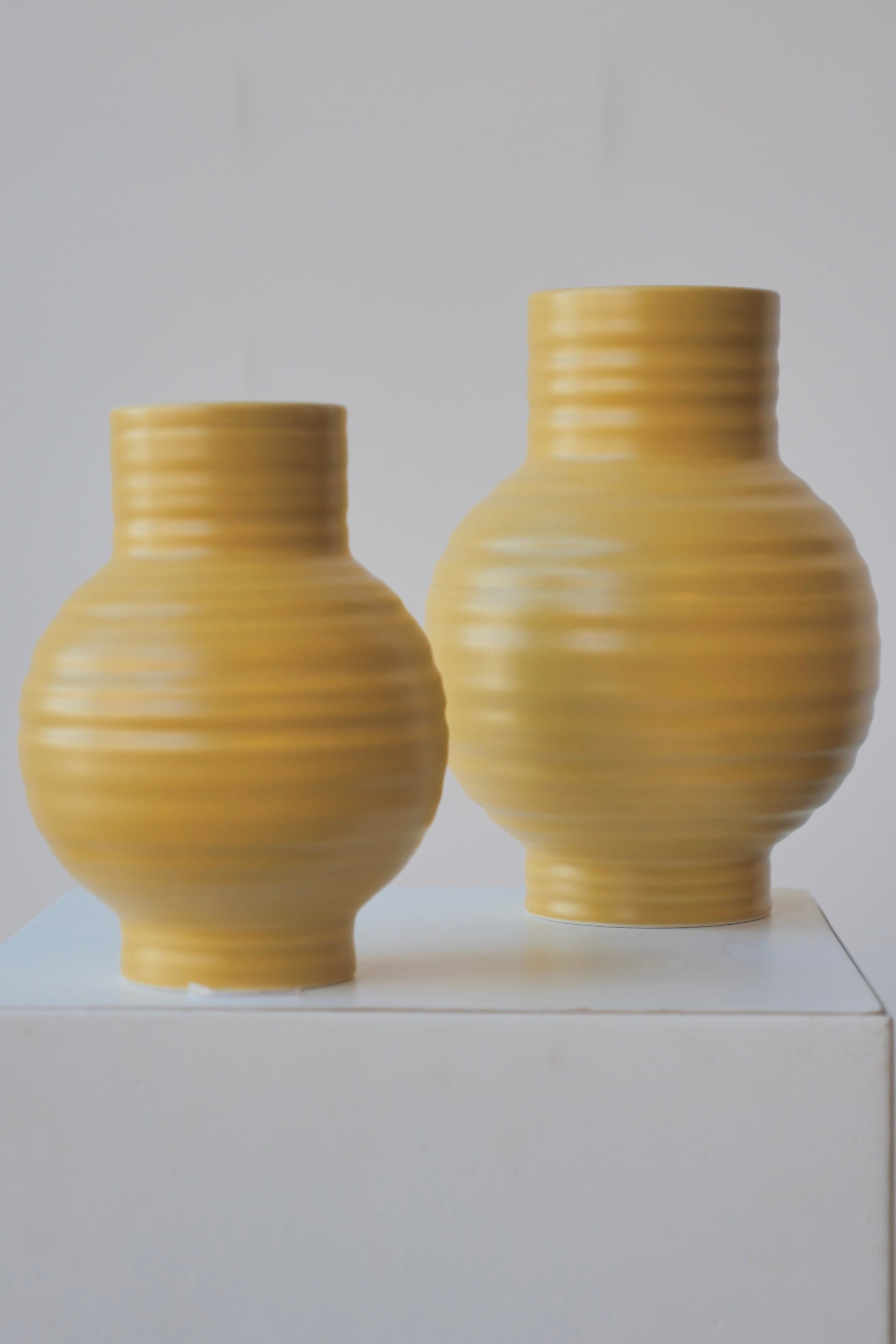 A pair of Mustard Essential Vases by Hawkins NY against a white wall. ©Sprout Home