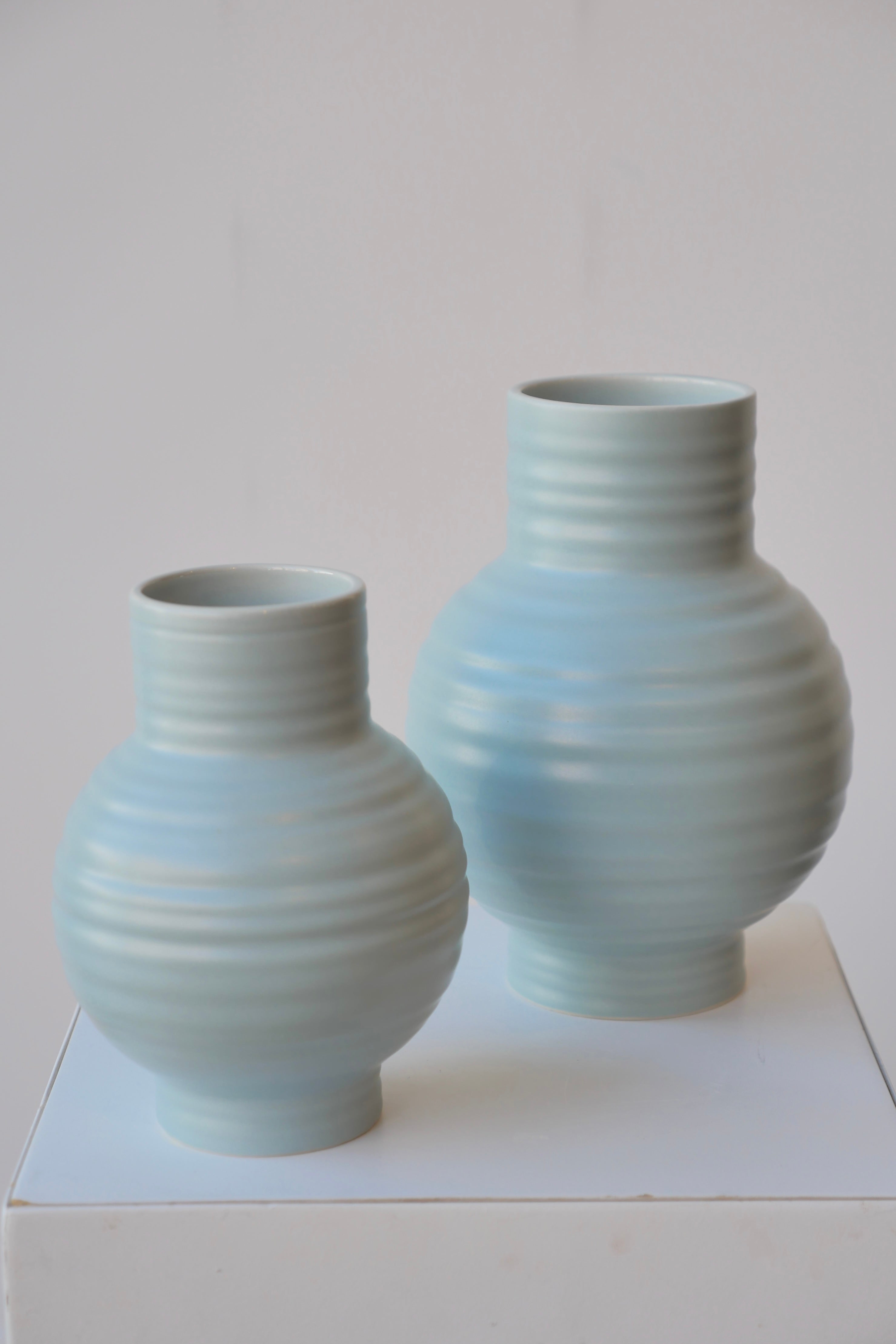 Pair of Essential Sky ceramic vases viewed from top side against white.