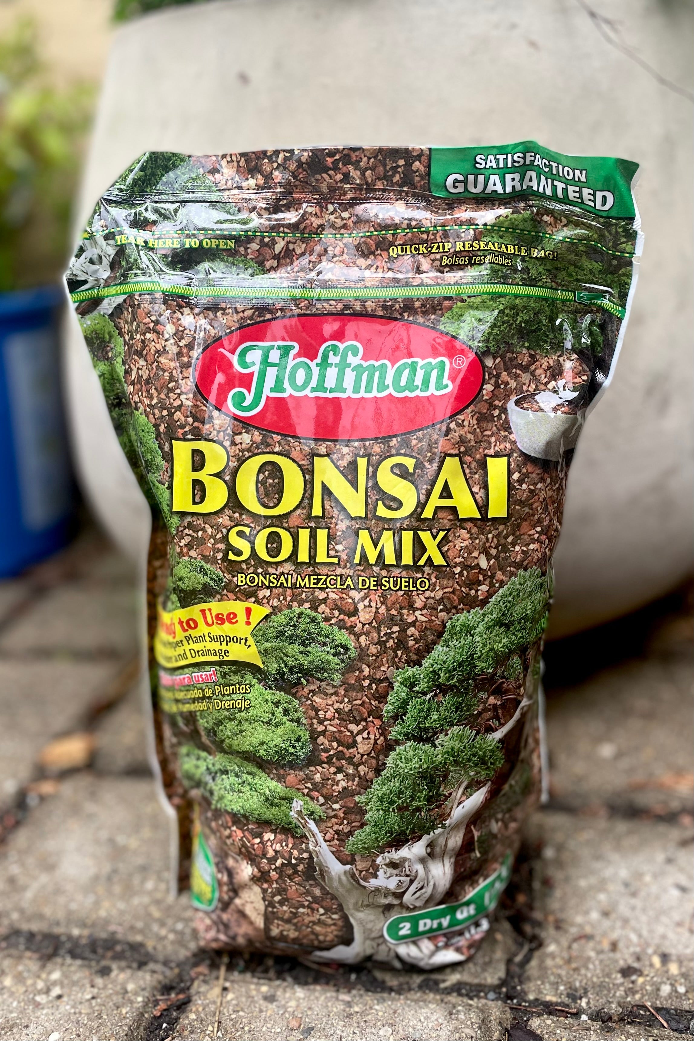 A full frontal view of Hoffman Bonsai Mix 2qt surrounded by plants