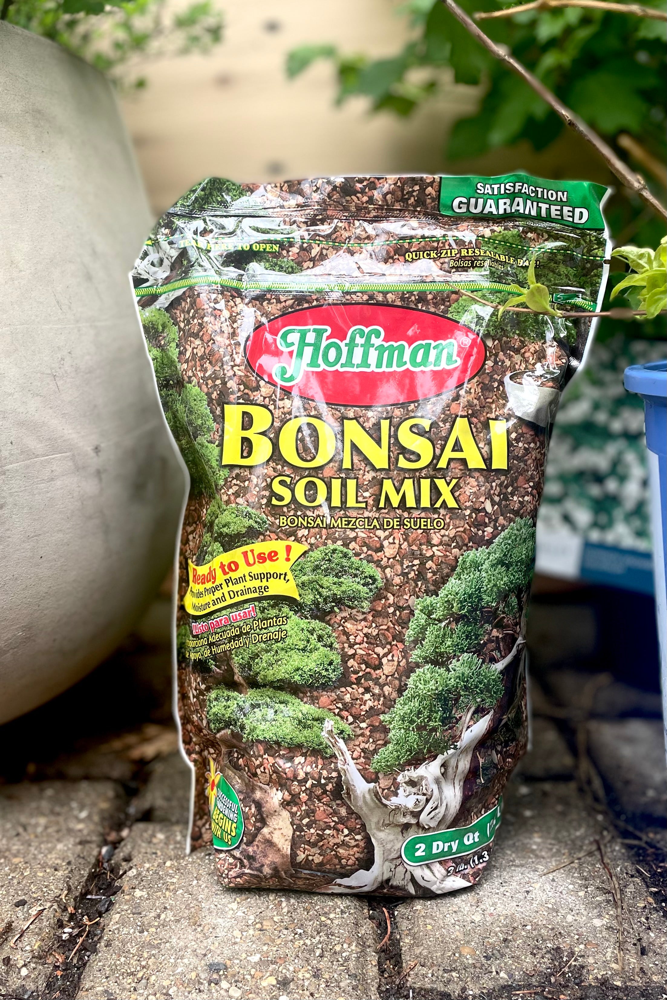A full frontal view of Hoffman Bonsai Mix 2qt surrounded by plants