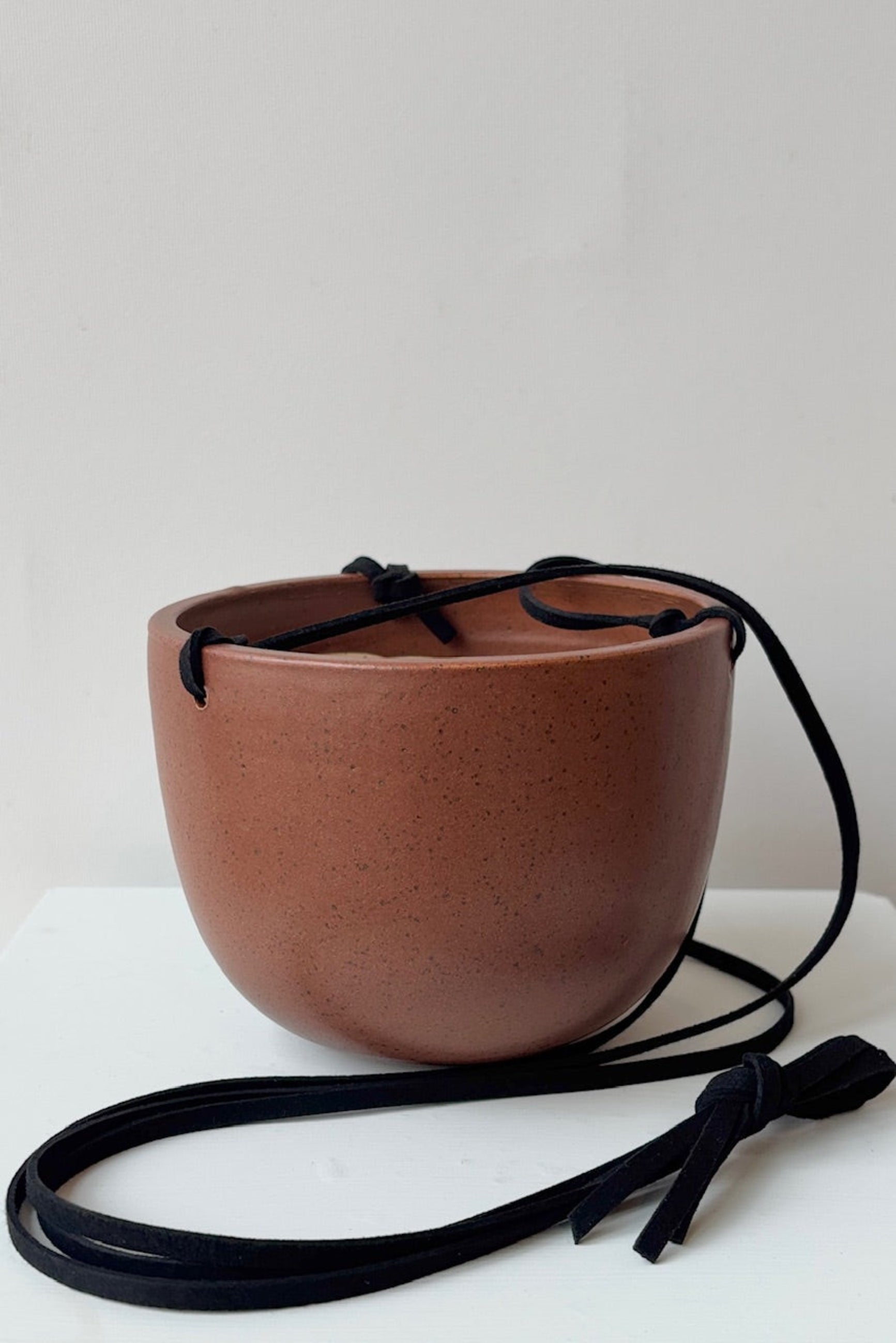 Brown ceramic bowl with black speckles and a black strap on a white background ©Sprout Home