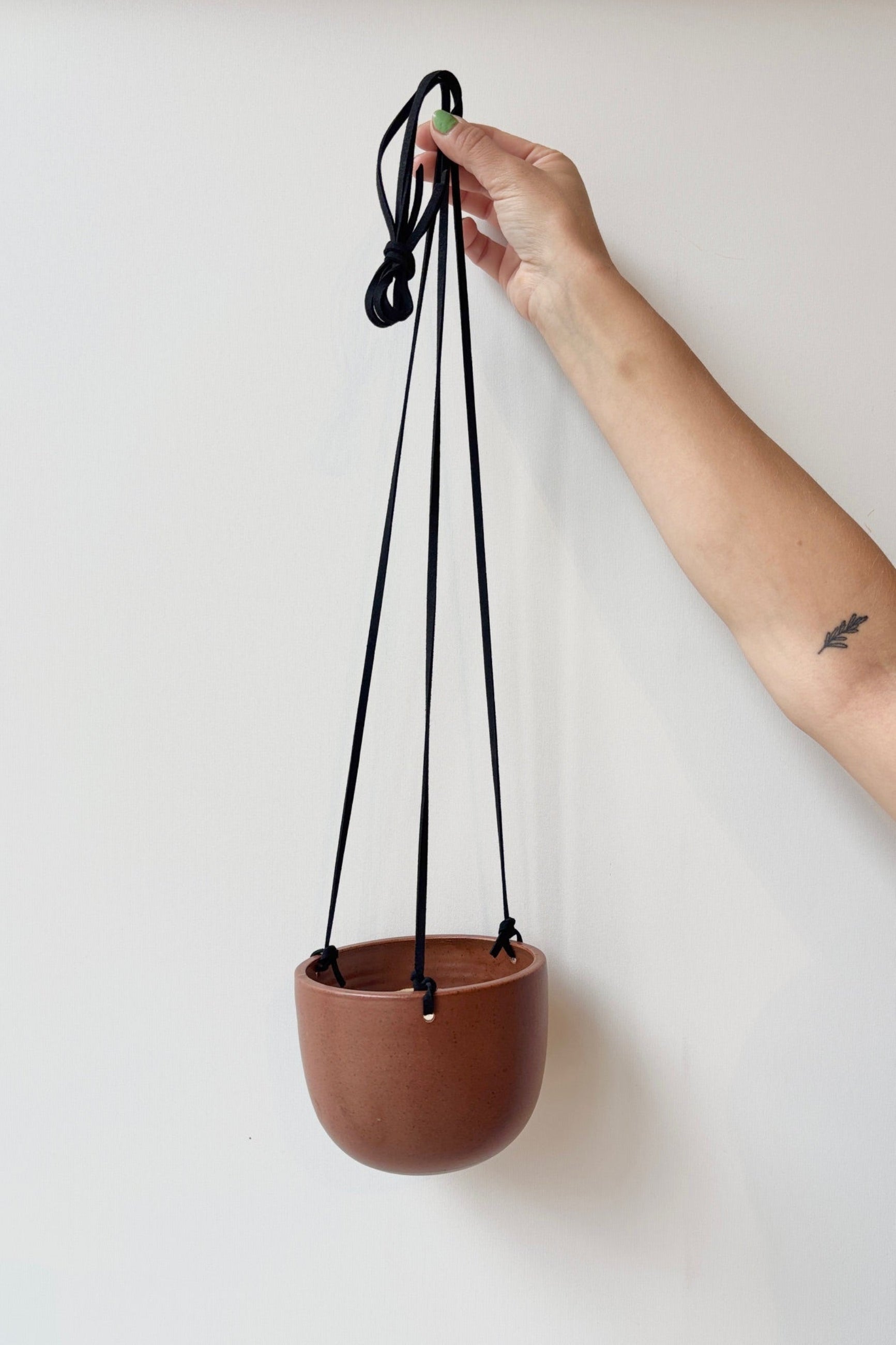 Brown hanging planter with black speckles and a black cord against a white background ©Sprout Home