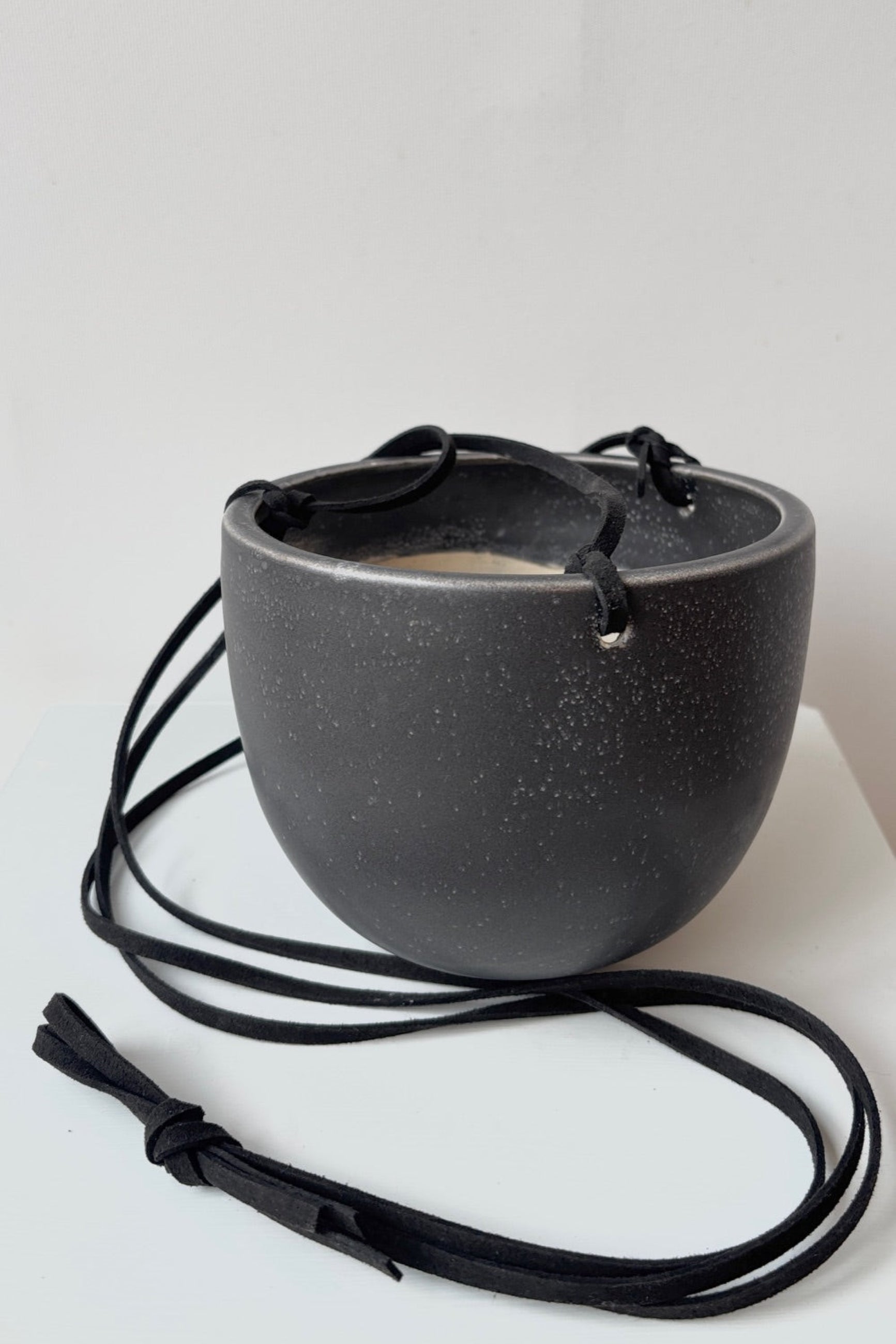 Black ceramic bowl with white speckles a black cord on a white background ©Sprout Home