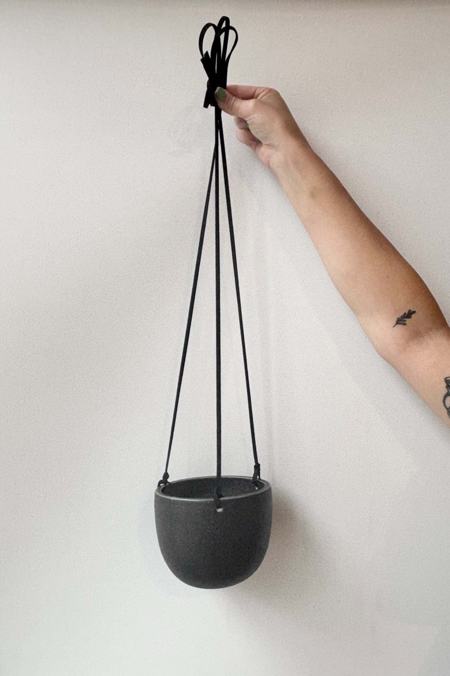 Person holding a black ceramic hanging planter with white speckles against a white wall ©Sprout Home