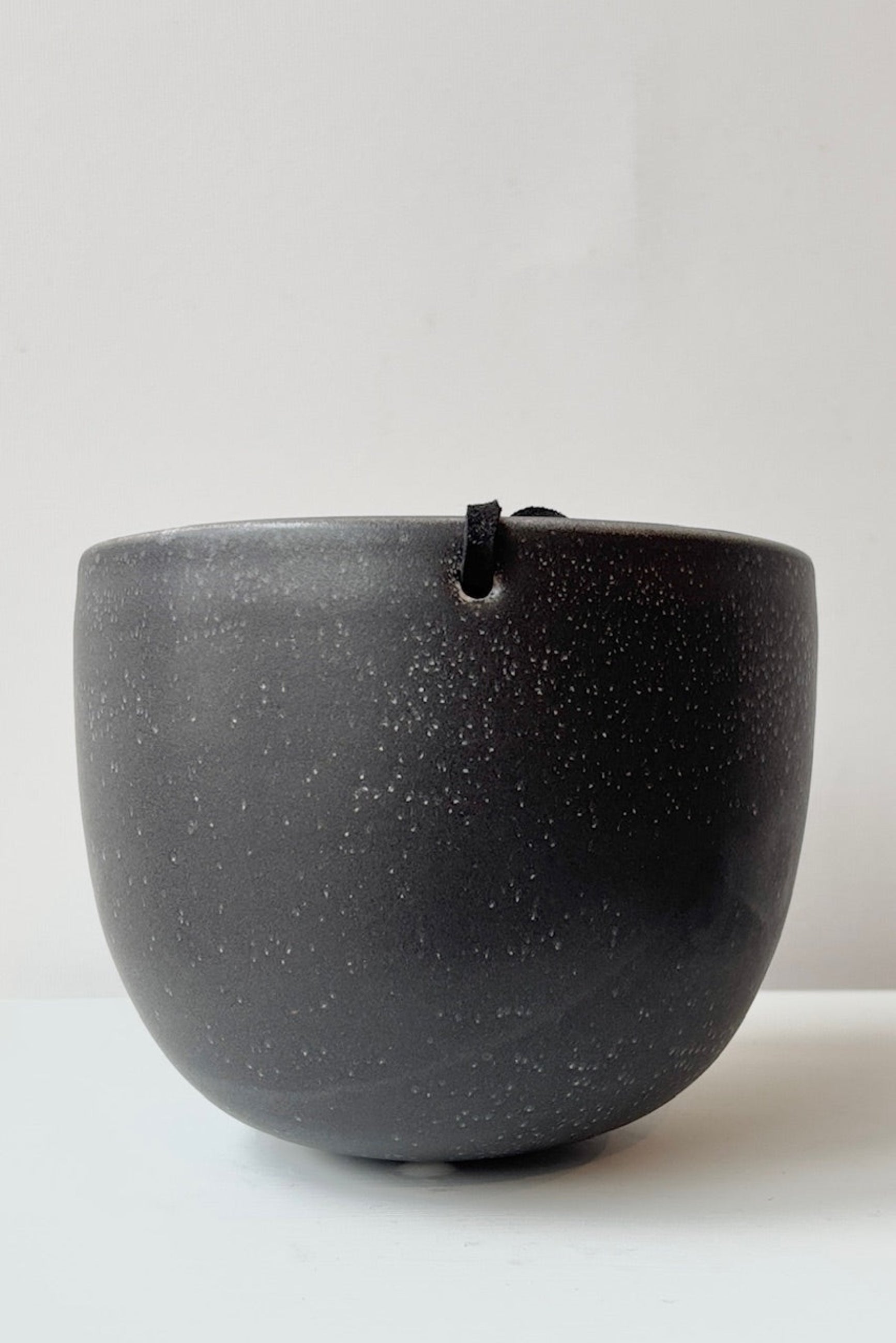 Black speckled ceramic hanging pot on a white background