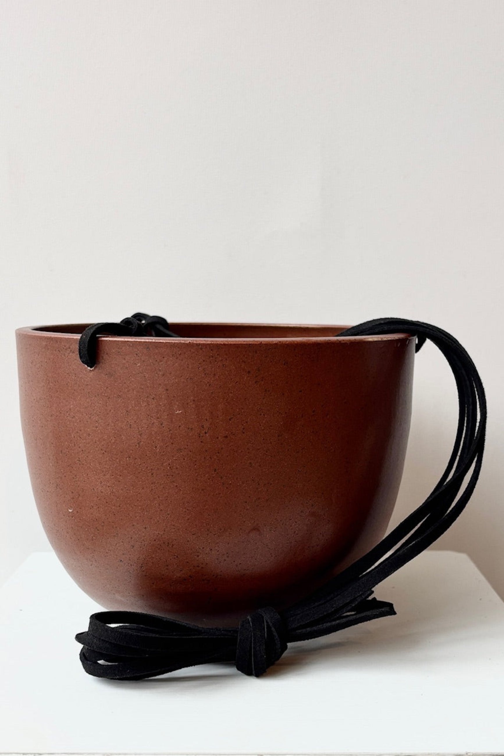 Brown ceramic hanging pot with black speckles and a black cord against a white background ©Sprout Home