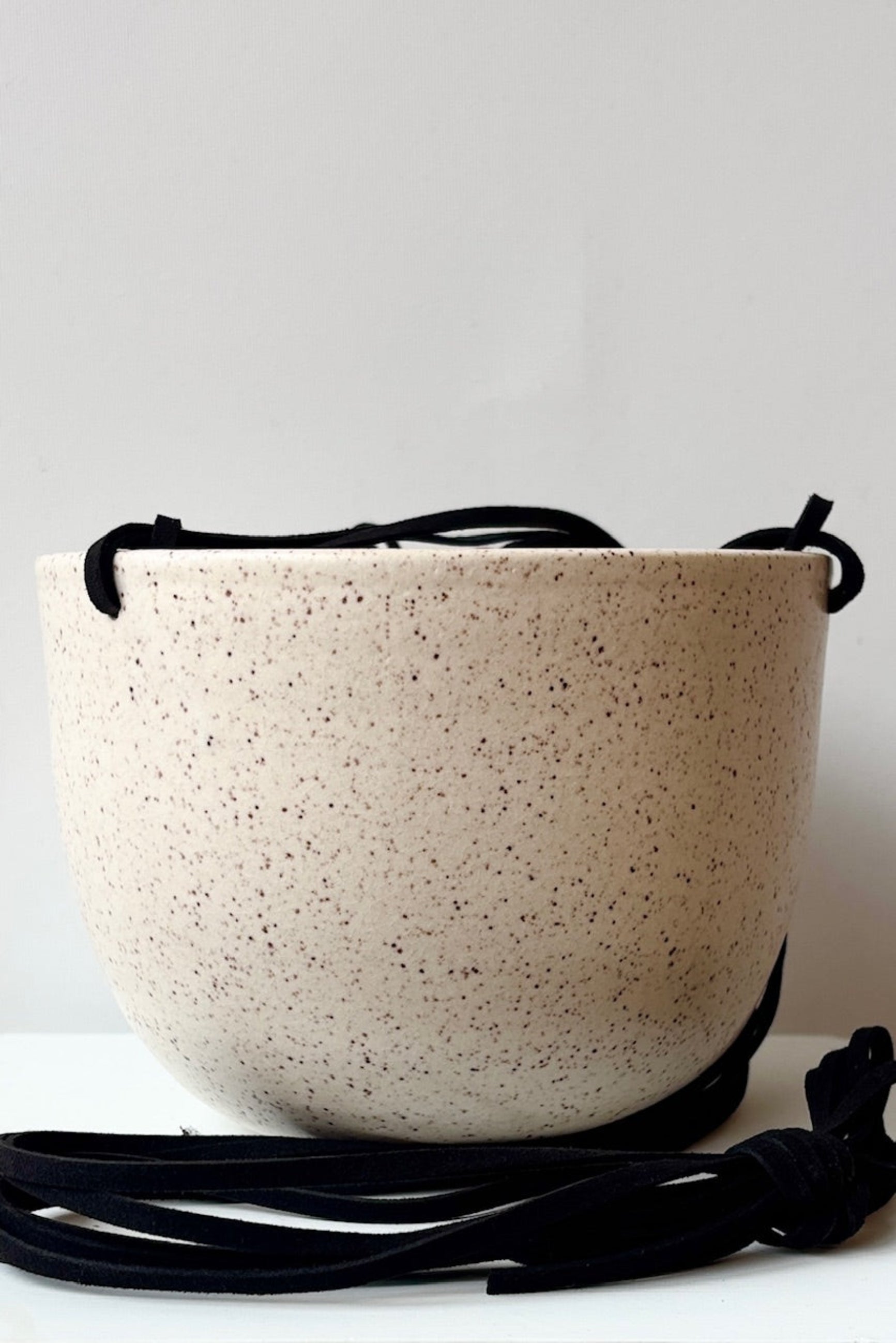 Speckled cream ceramic bowl with a black cord on a white background ©Sprout Home