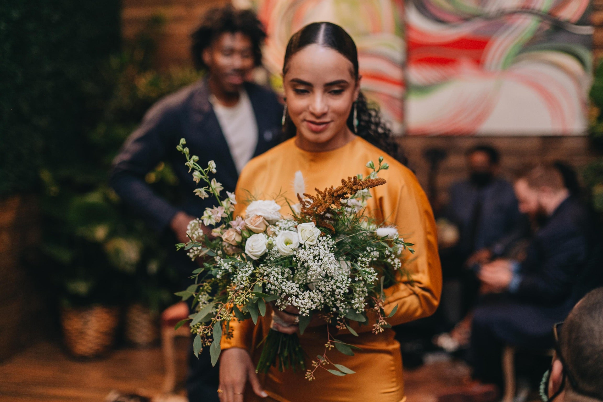 Sprout Home wedding bouquet being held by the bride in terracotta orange. Photograph by Chuck Olu-Alabi