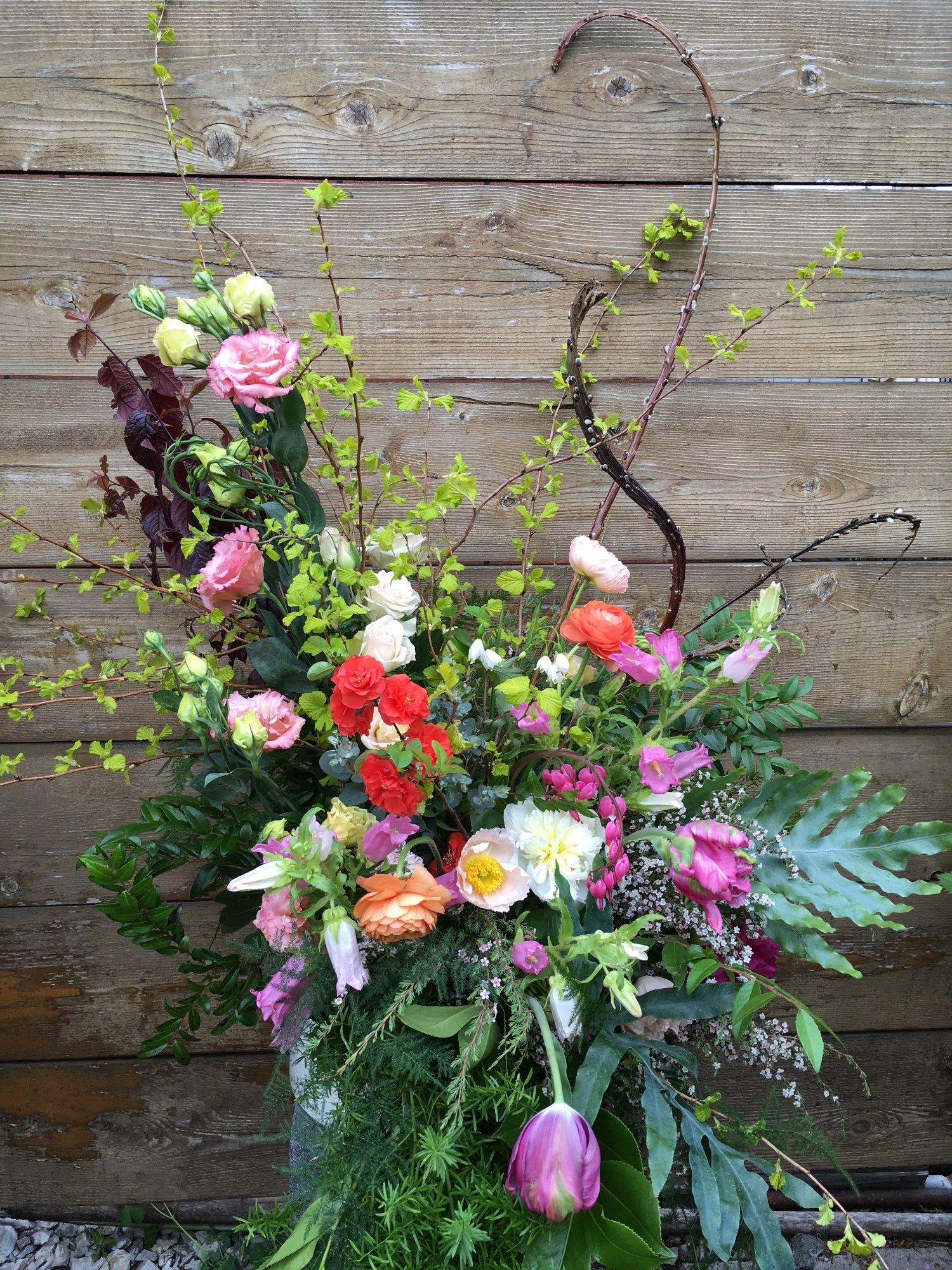 Floral installation in a garden style against a wood backdrop by SPROUT HOME.