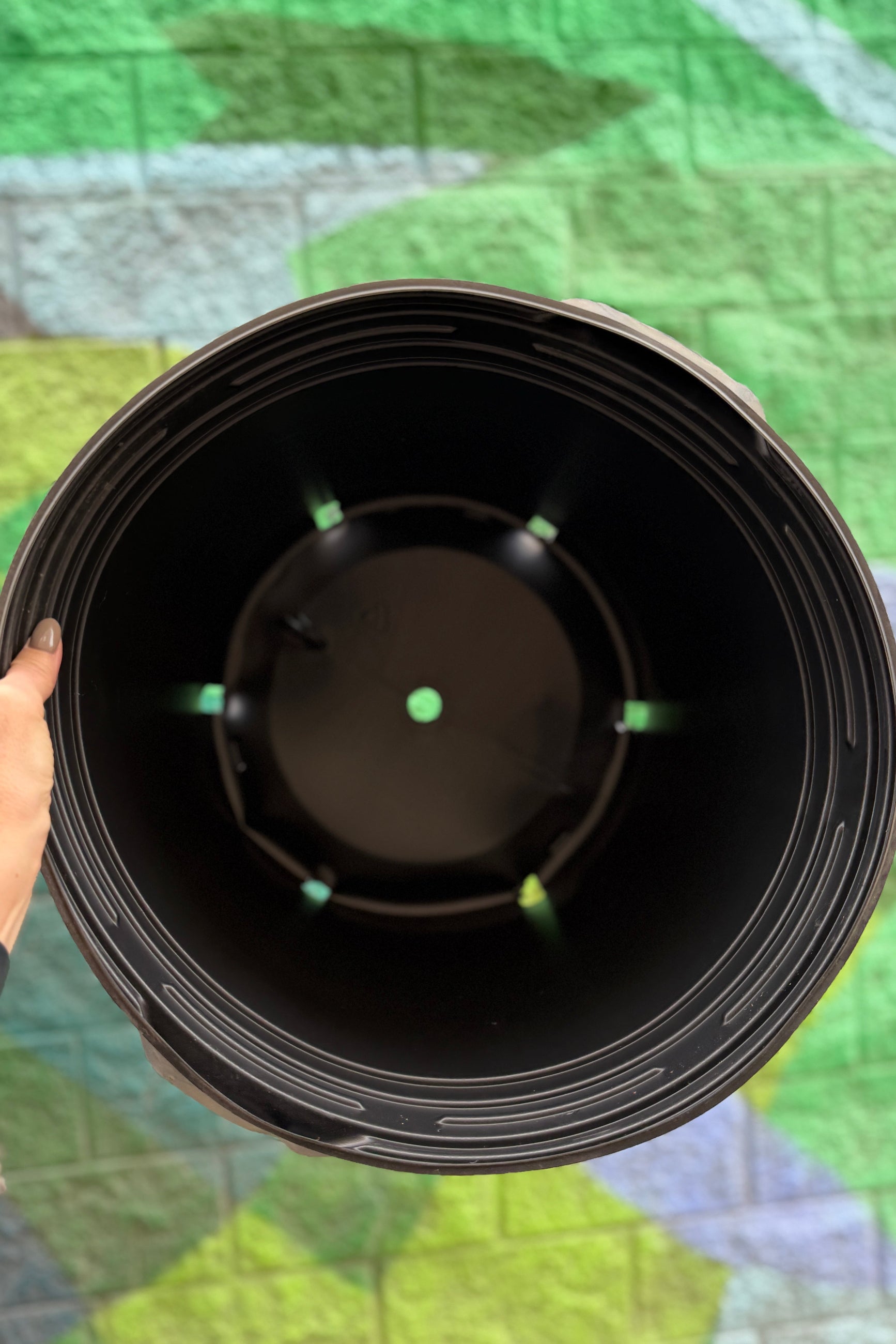 Nursery Pot 10 Gallon (15.75" dia) being held against a graphic wall and showing the inside drainholes ©Sprout Home