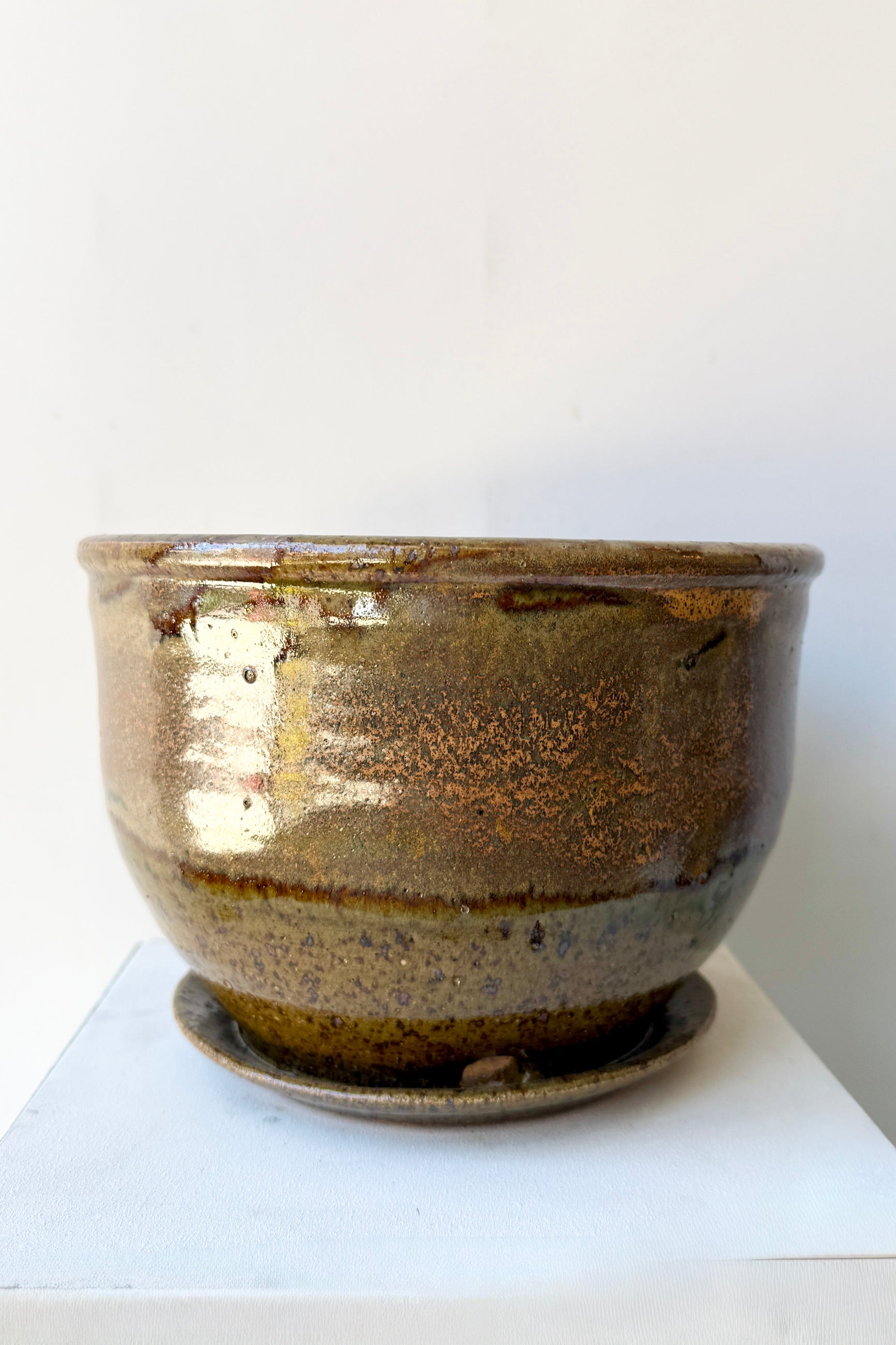 Ceramic 8" Bruning pot in an Army Green with Yellow speckled glaze on a stone surface. ©Sprout Home