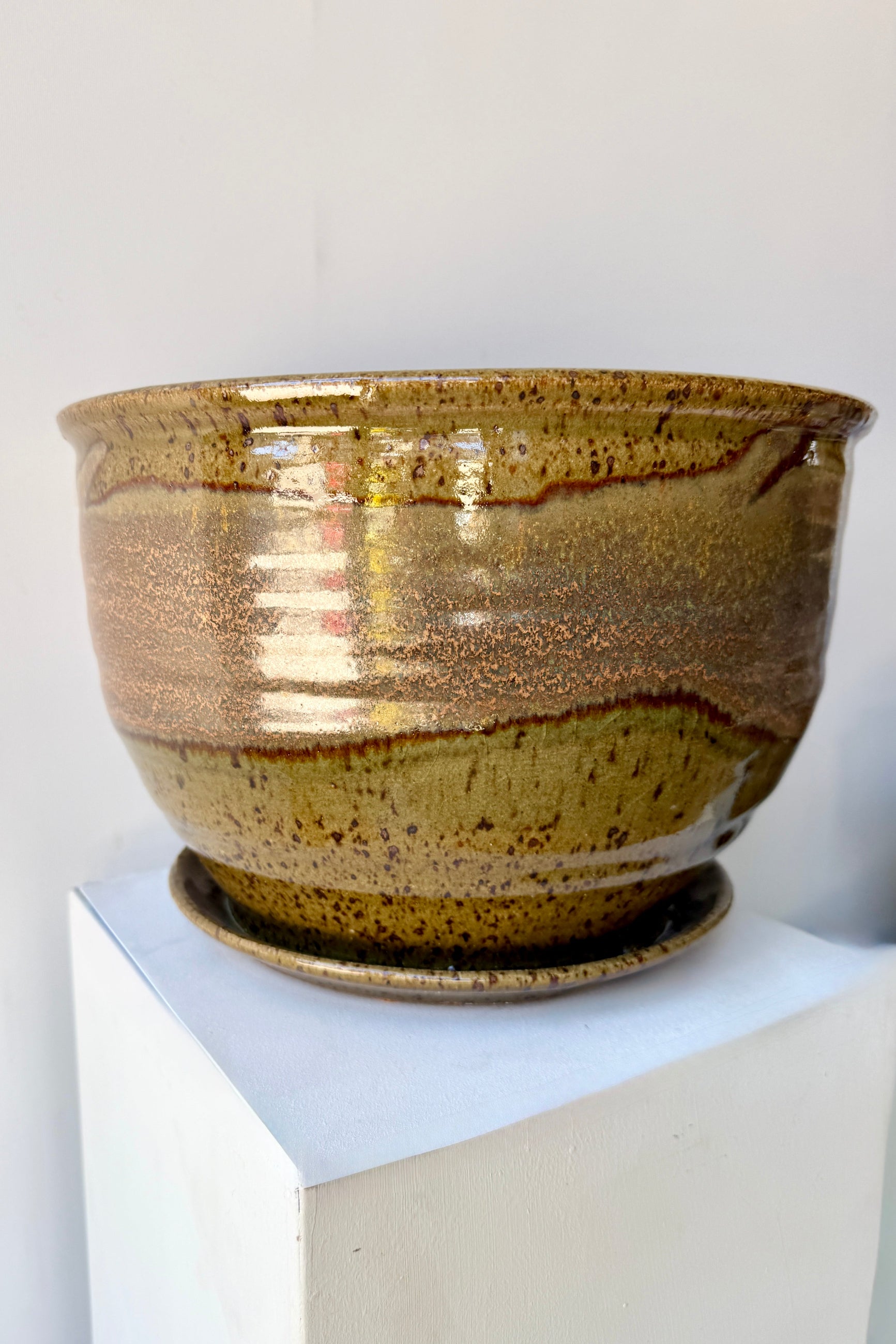 Ceramic 10" Bruning pot in an Army Green with Yellow speckled glaze on a stone surface. ©Sprout Home