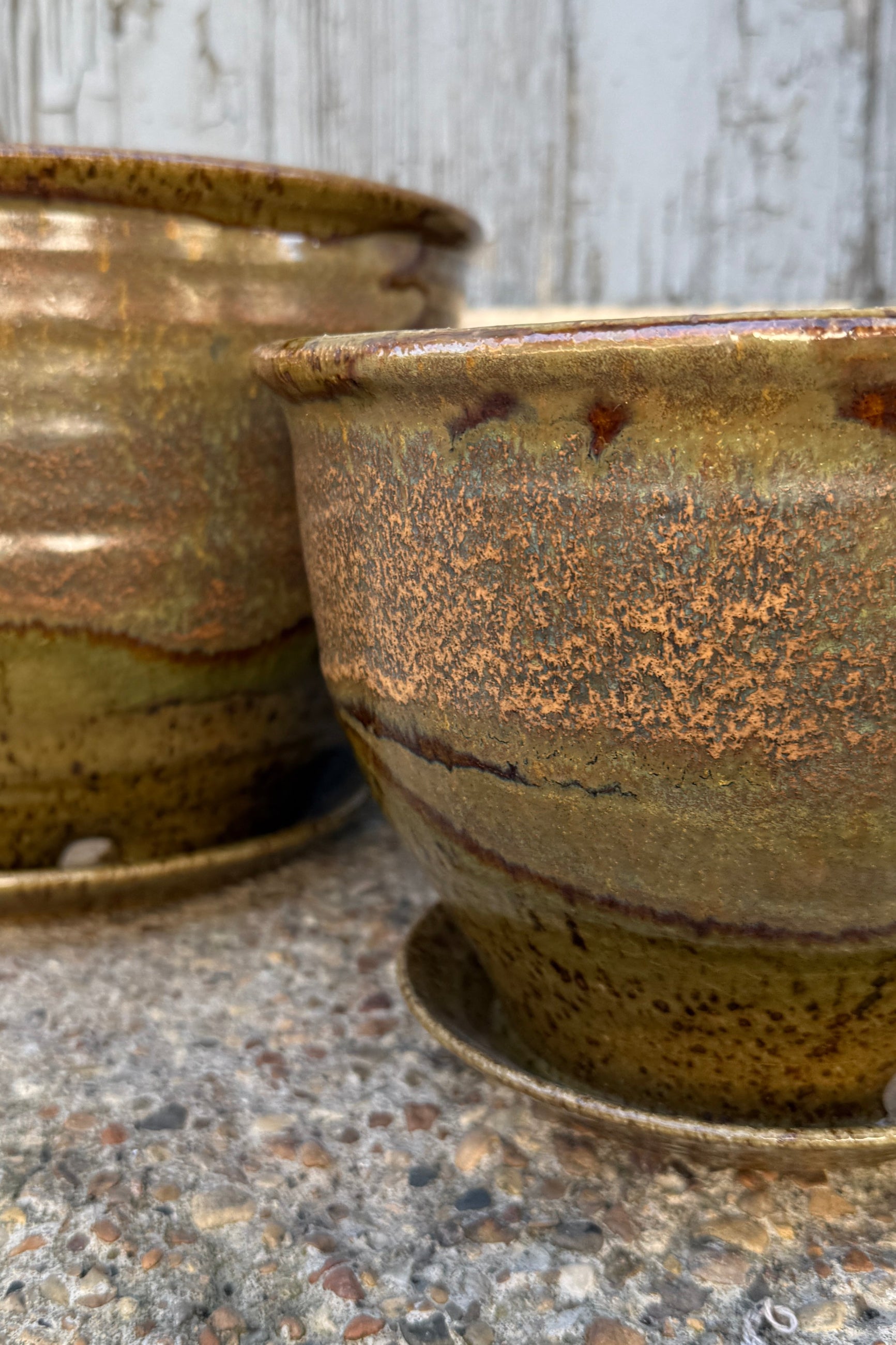 Ceramic Bruning pots in an Army Green with Yellow speckled glaze up close on a stone surface. ©Sprout Home