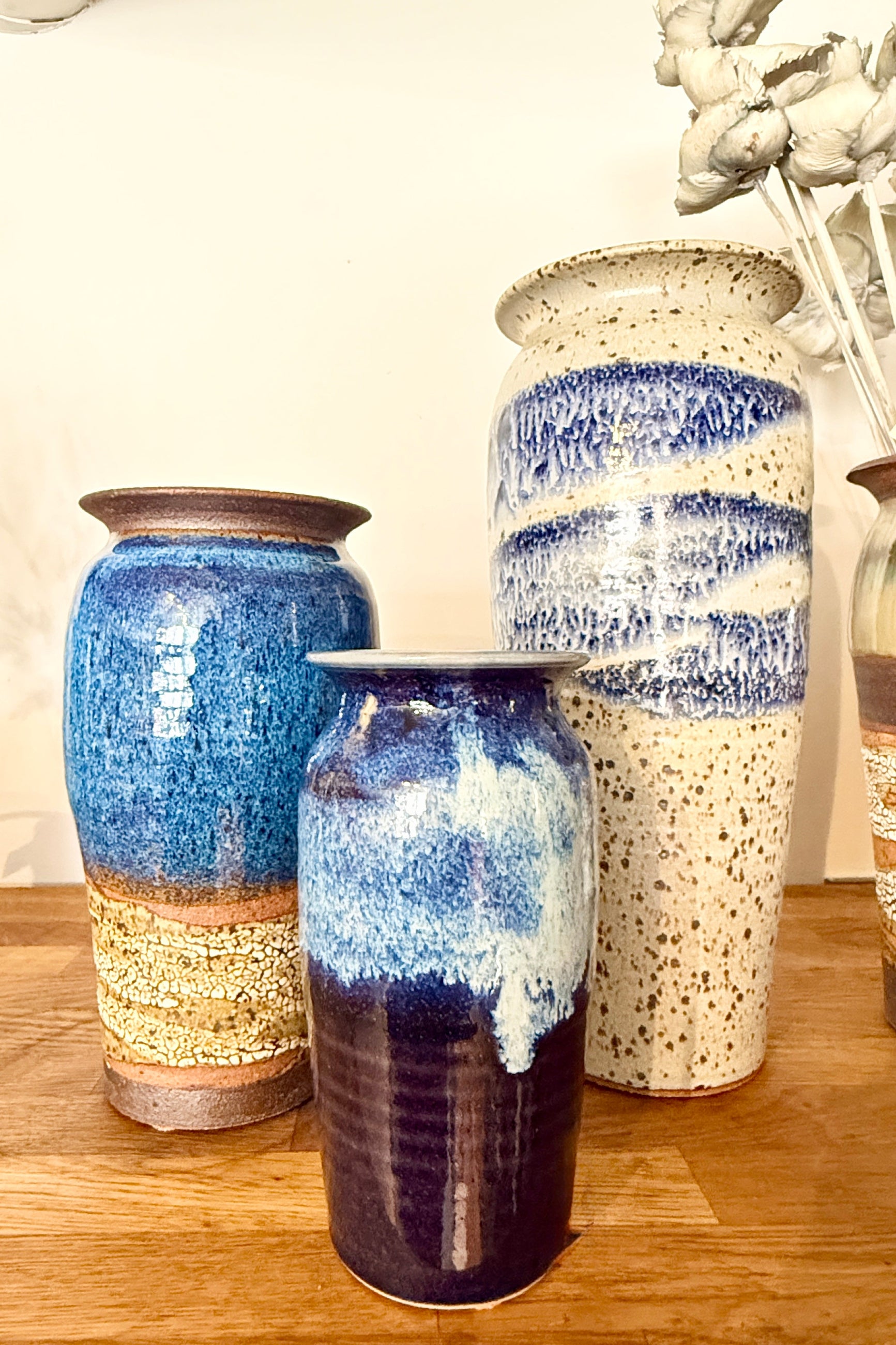 Set of Bruning Pottery three ceramic vases with blue and white glaze on a wooden surface. ©Sprout Home