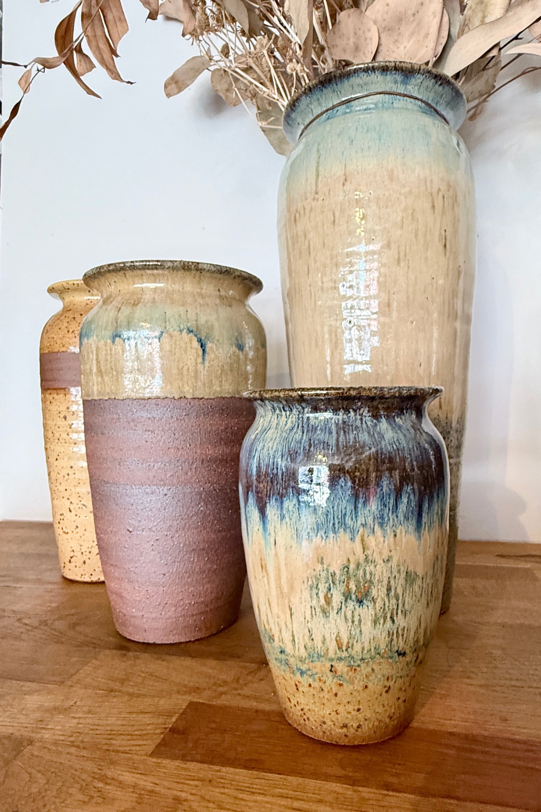 Set of Bruning Pottery ceramic vases with textured shades of beige, but and plum glaze on a wooden surface ©Sprout Home