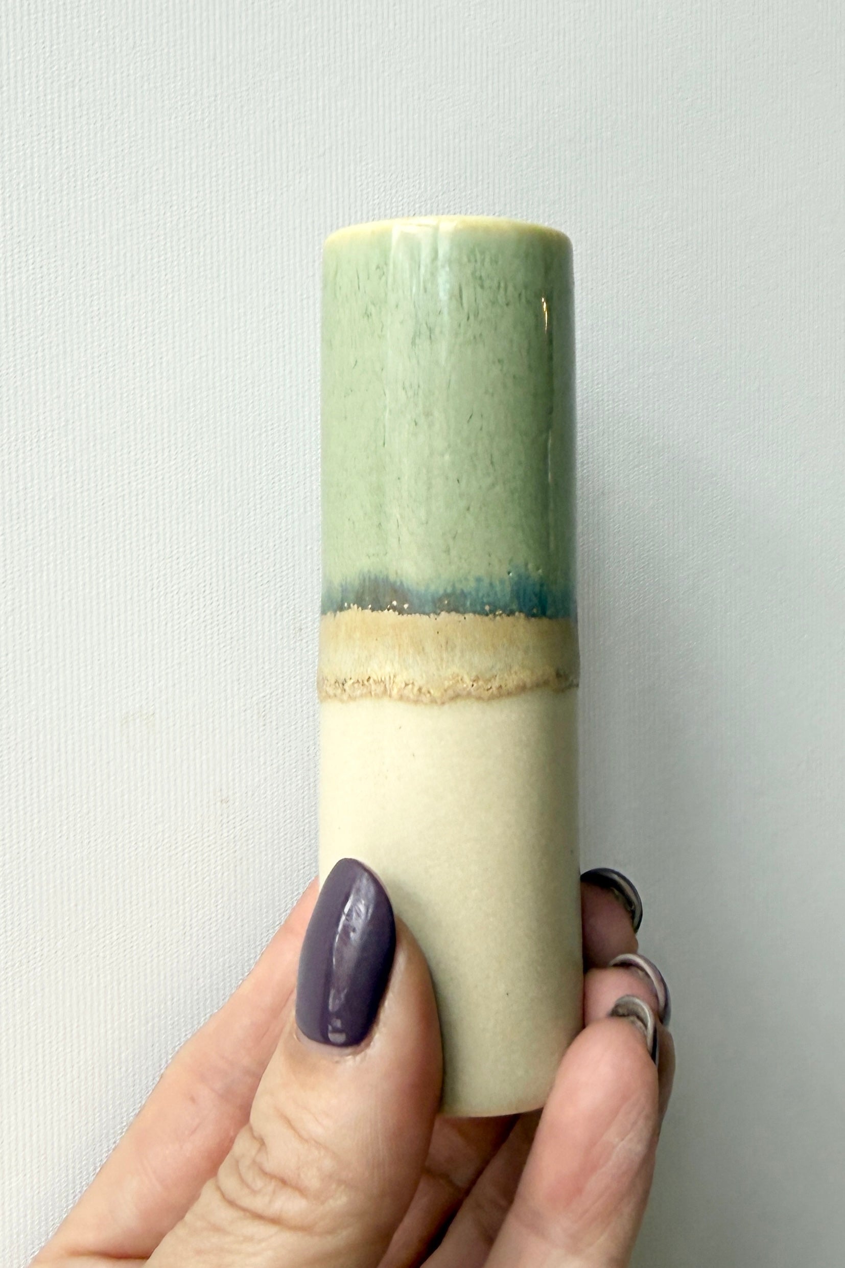 Hand holding a cylindrical SGW vase with gradient colors against a plain background ©Sprout Home