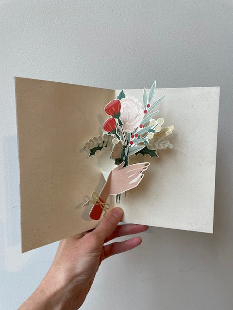 Hand holding pop up card with interior of card open.