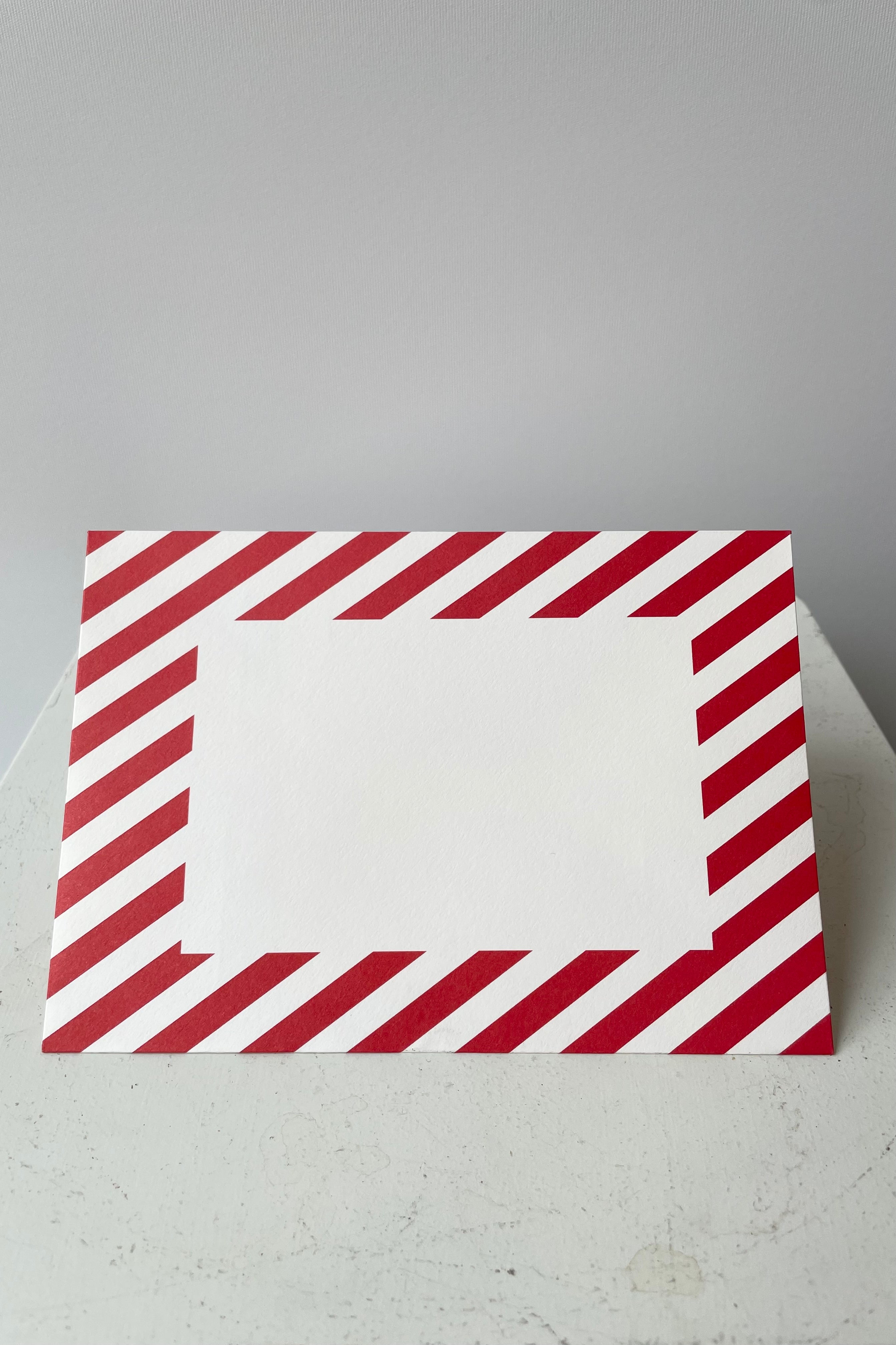 Red and white striped envelope with blank white rectangle on face of envelope.