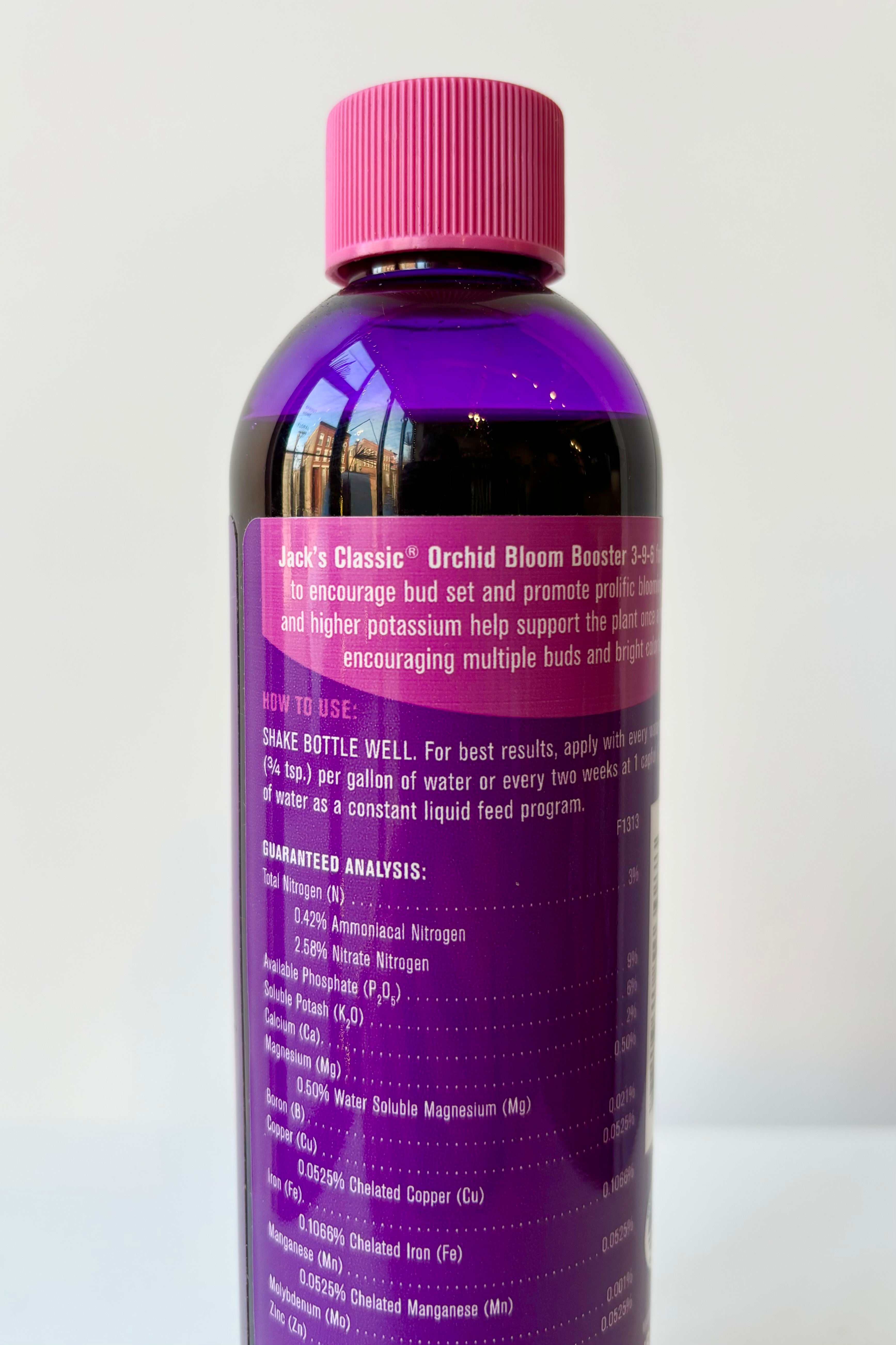 Backside of Jacks Classic 8oz liquid orchid fertilizer in purple bottle against white background