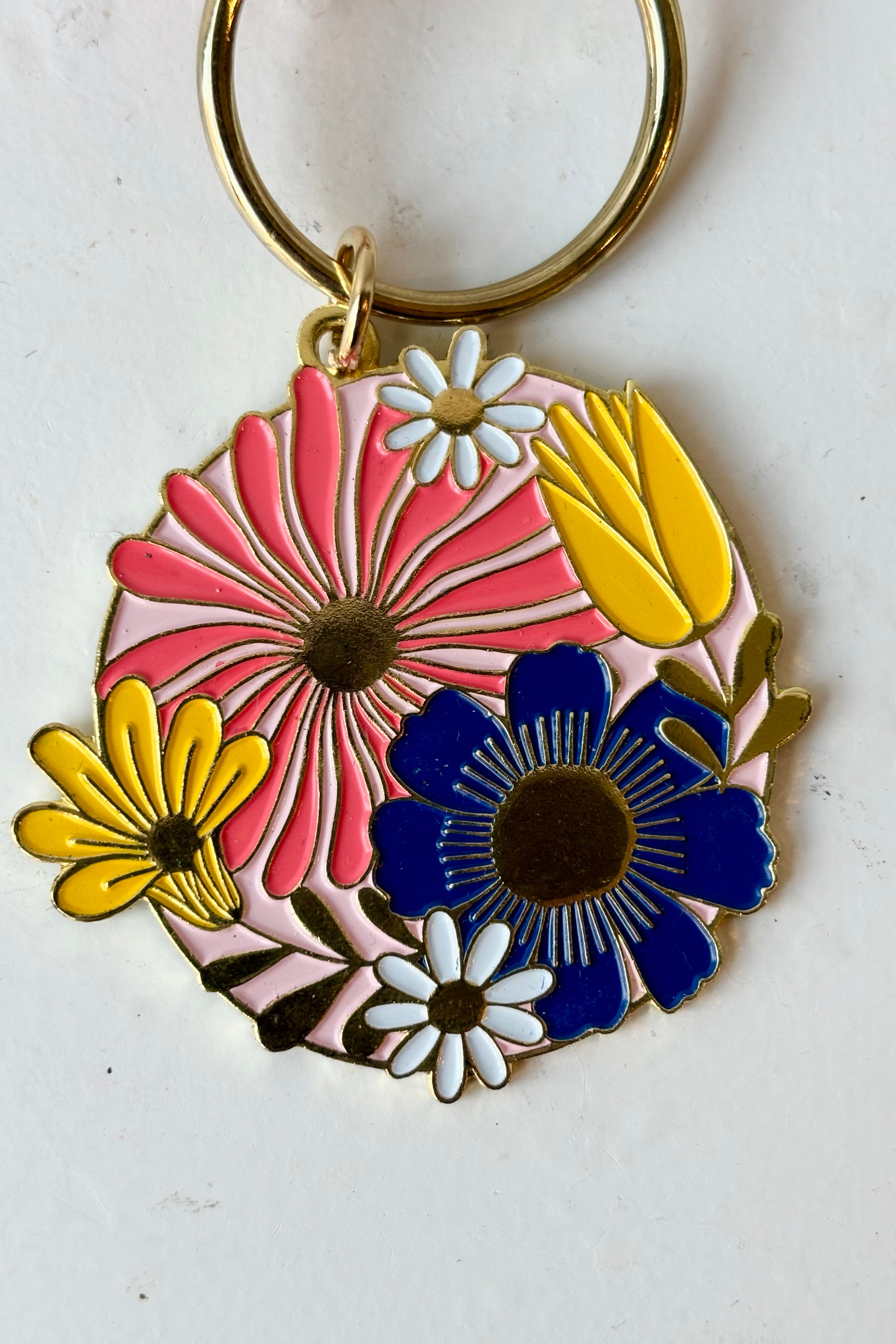 Close up of Cottage floral keychain featuring round floral motif in pink, yellow and blue on gold keychain