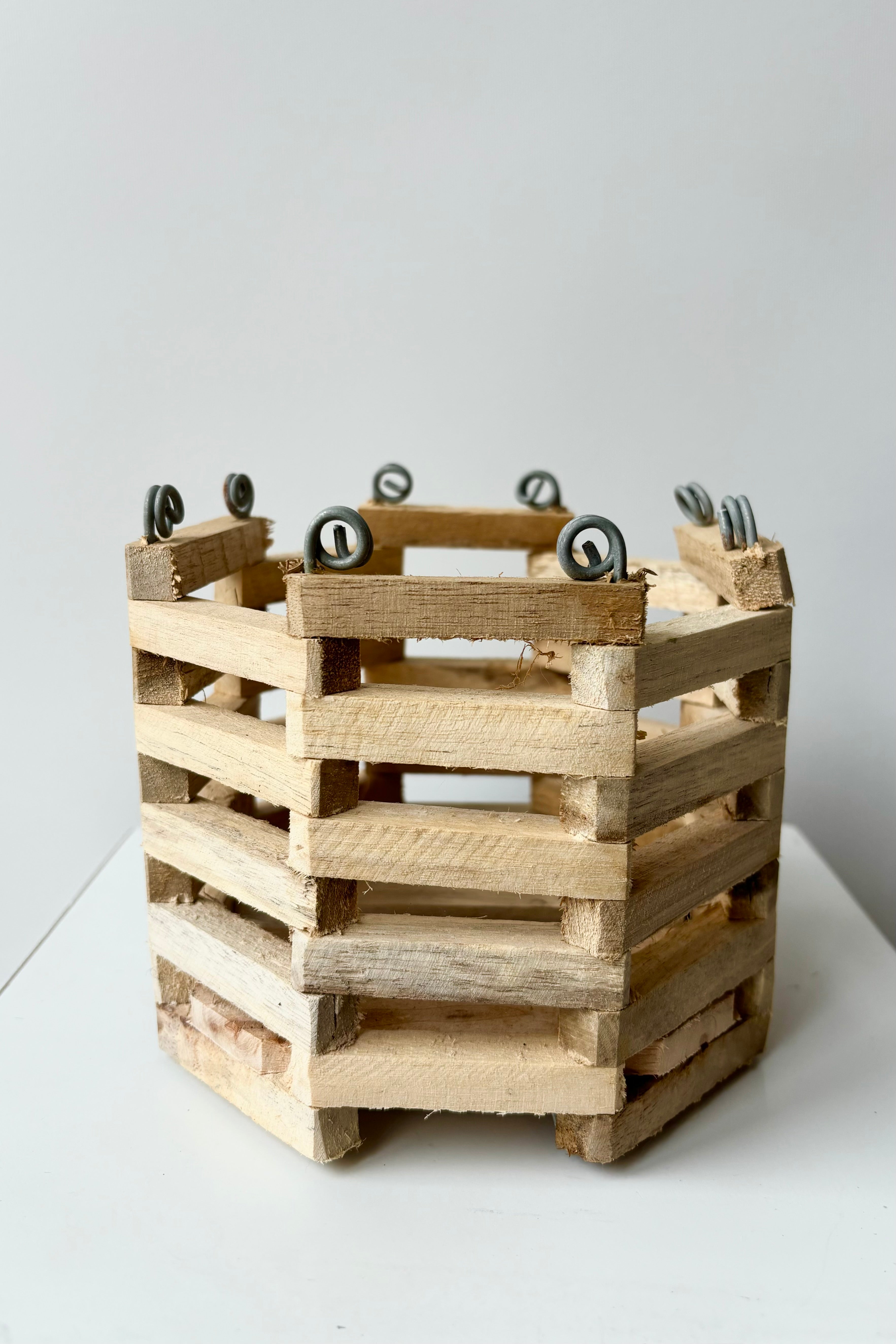 Front view of octagonal slatted basket with metal rings for string attachment, not included, against white background