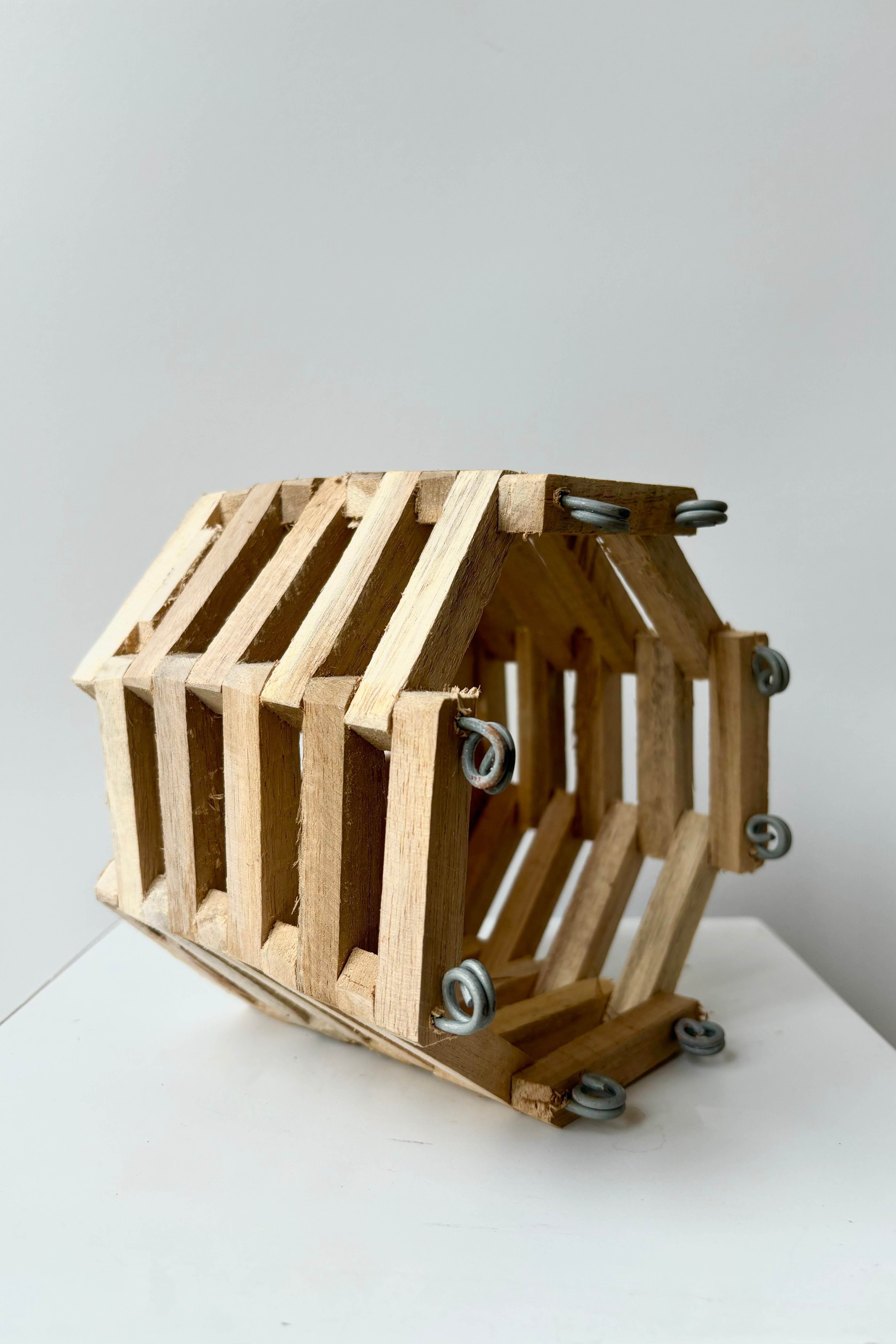 Side view of octagonal slatted basket with metal rings for string attachment, not included, against white background