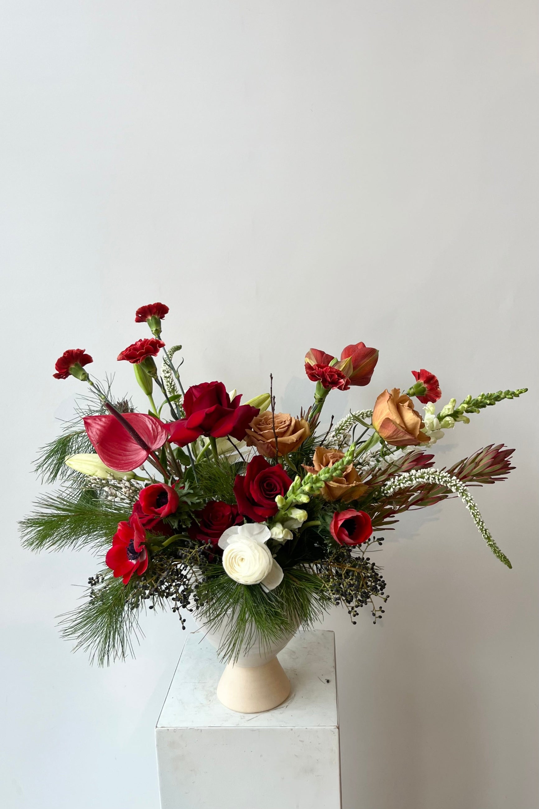 A hand holds an example of fresh Floral Arrangement Solstice large and in charge with shades of red from Sprout Home Floral in Chicago ©Sprout Home #size_$200