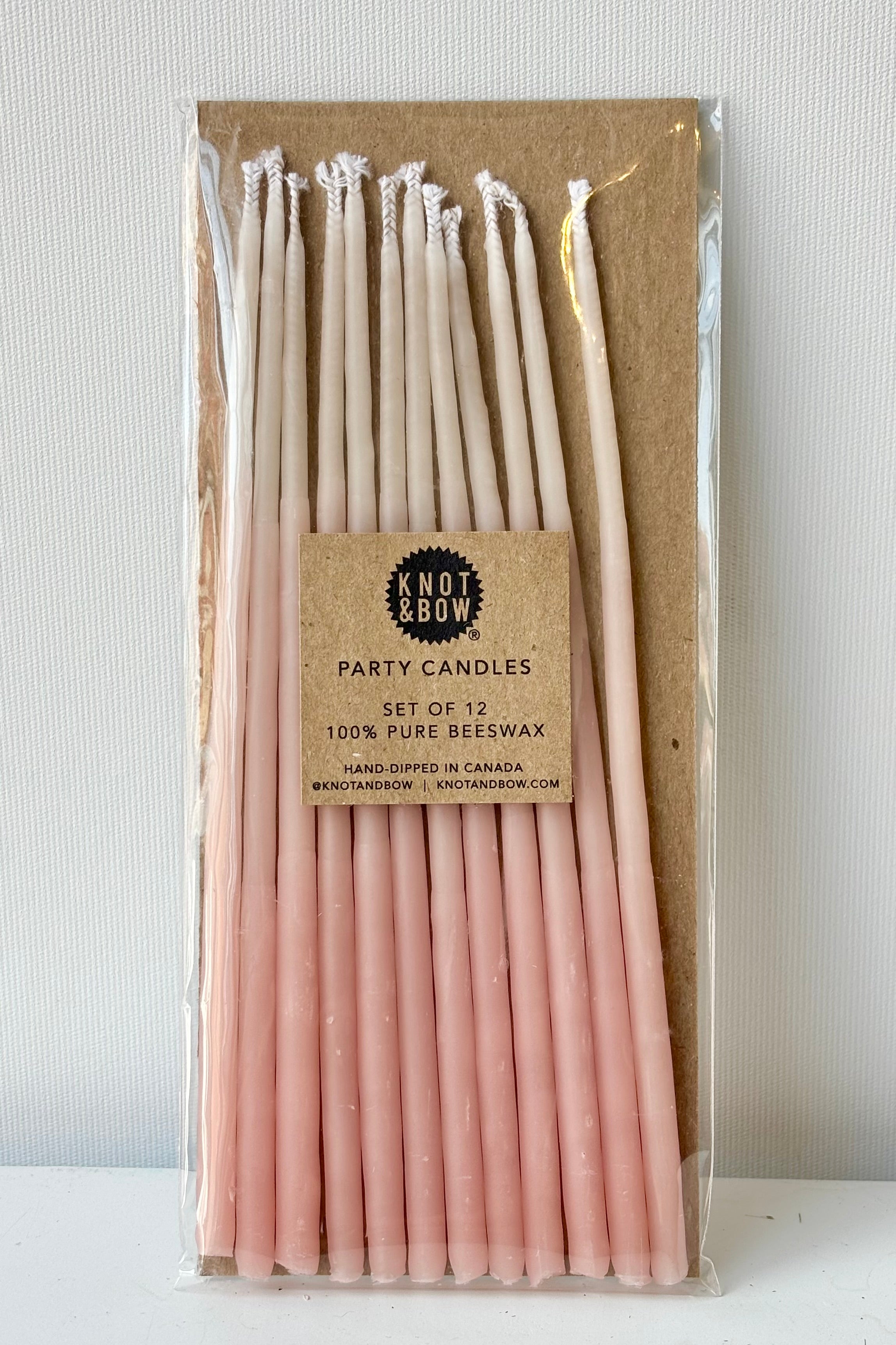 Set of twelve tall ombre pink candes against white background