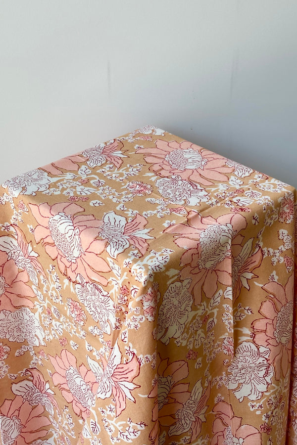 Hand block printed Panjim tablecloth with a gold and pink floral motif with maroon accents against white background.