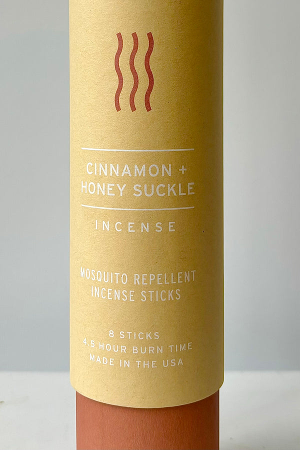 Detail of cardboard tube packaging with the words cinnamon and honeysuckle incense, mosquito repellent incense sticks, eight sticks, four and a half hour burn time, made in the USA