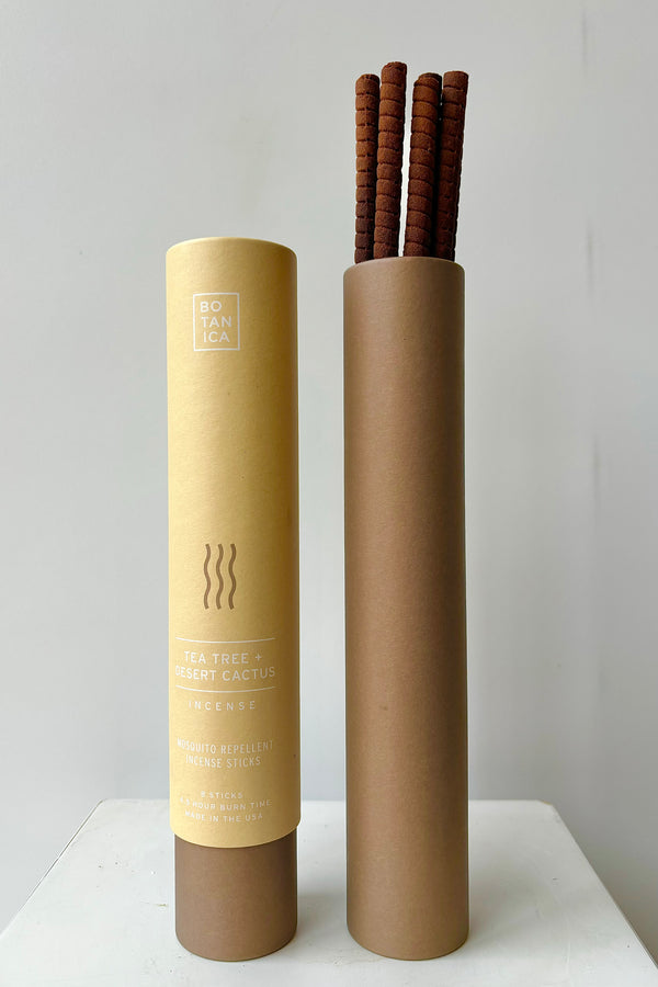Two kraft paper and brown colored cardboard tubes showing front of packaging and interior with tea tree and desert cactus incense sticks against white wall