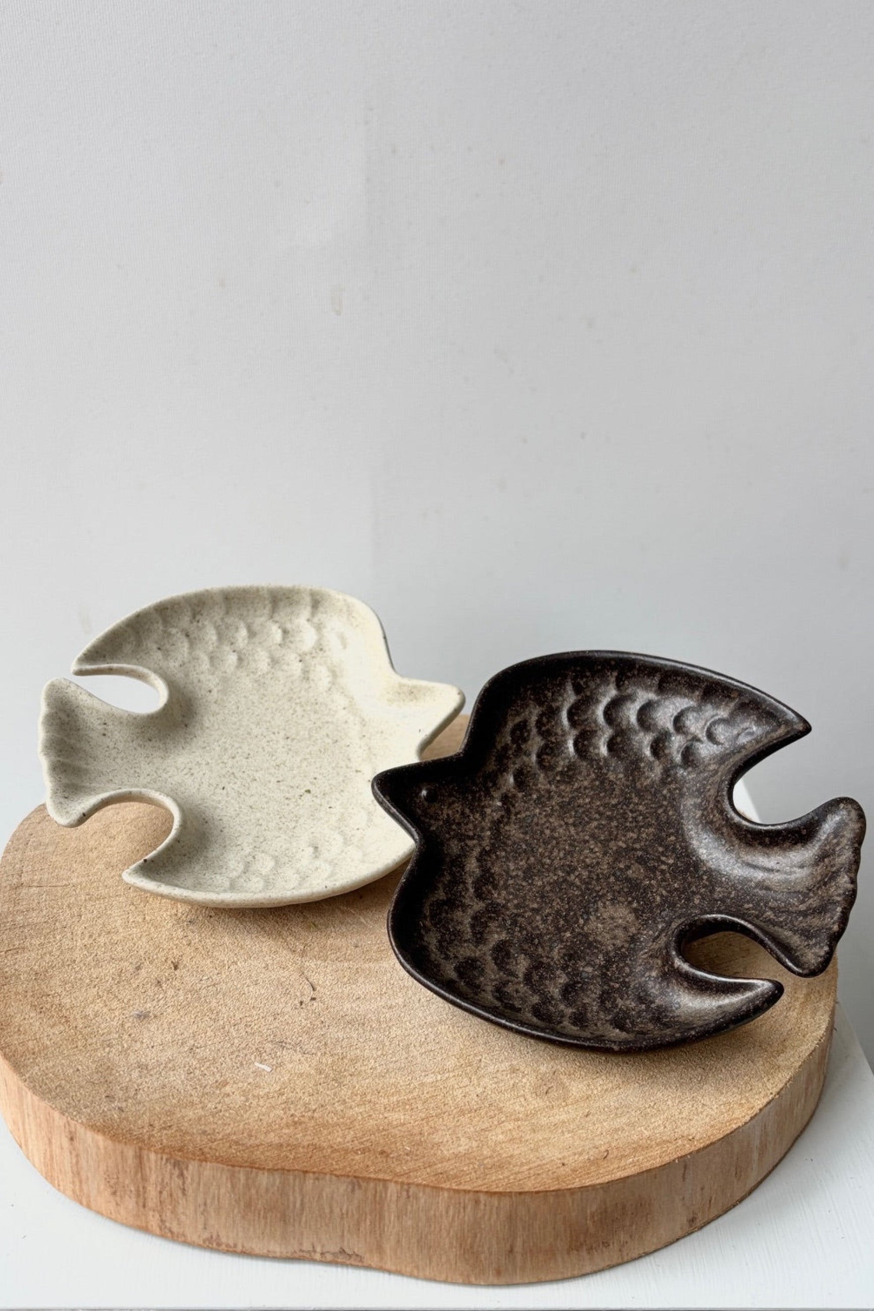 Two bird-shaped ceramic plates on a wooden stand with a plain background