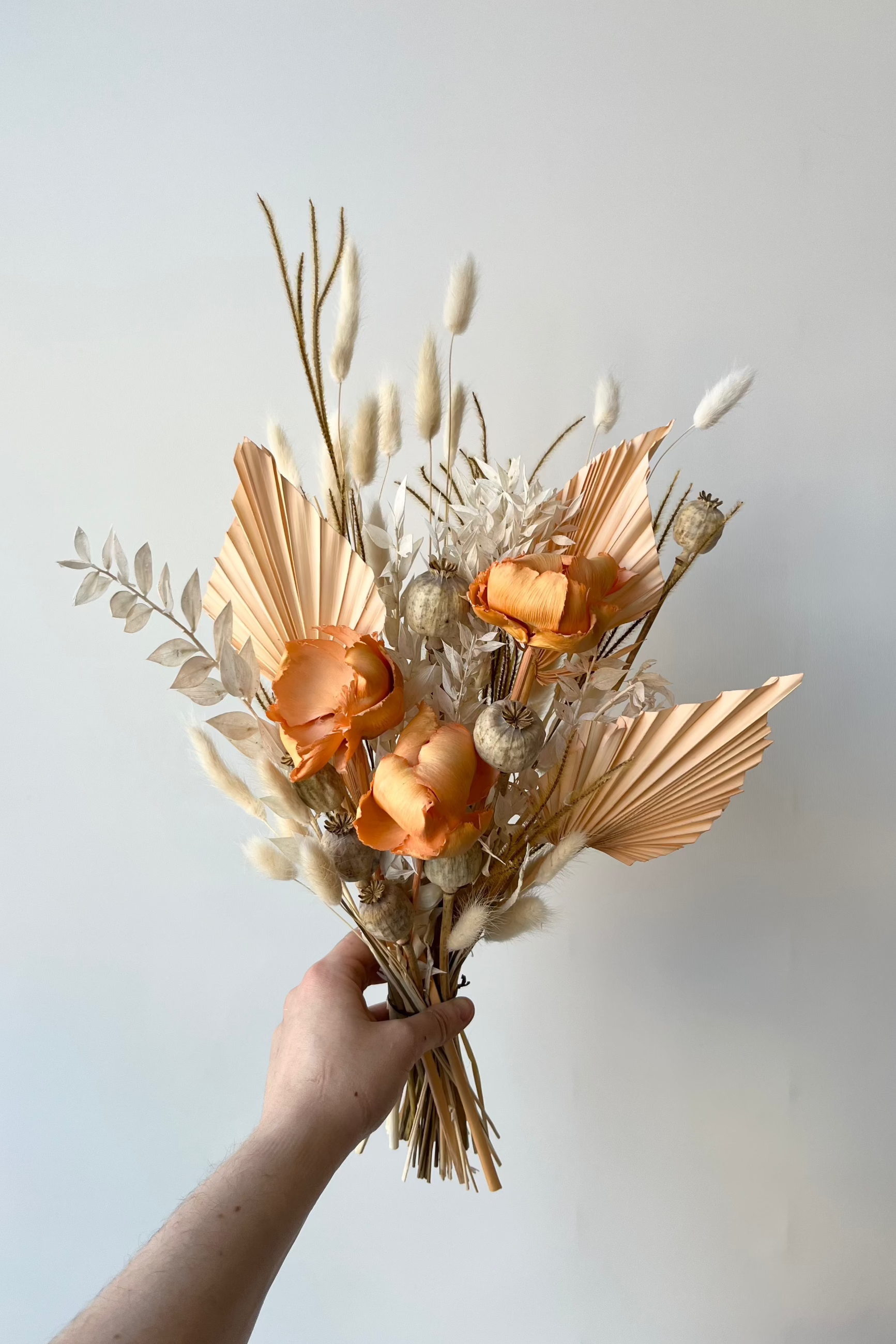 Creamsicle preserved floral arrangement by Sprout Home being held in hand against a white wall ©Sprout Home #size_$60
