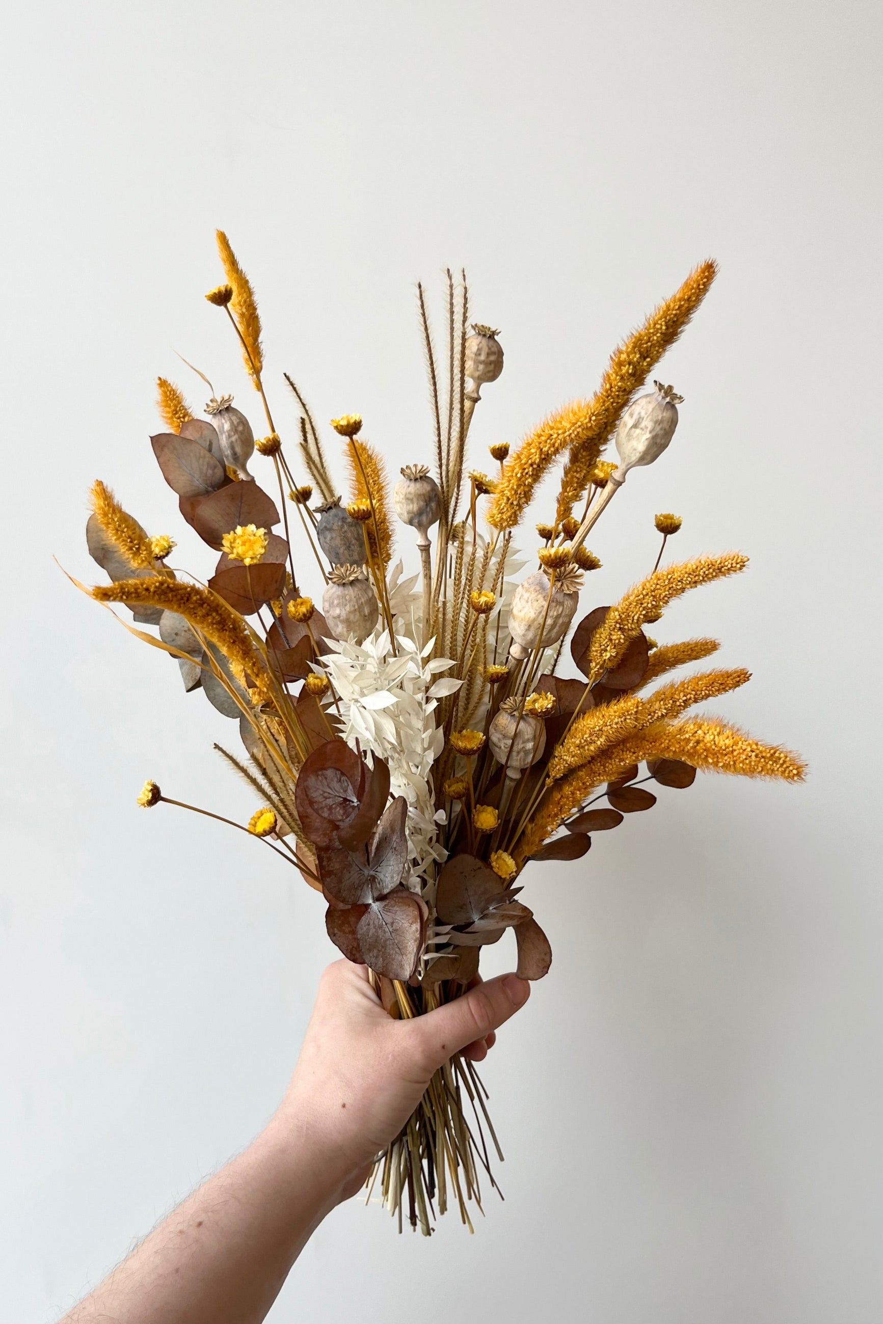 Golden Hour preserved arrangement by sprout Home being held in hand showing of the various textures of yellow and earth colored dried stems ©Sprout Home #size_$60