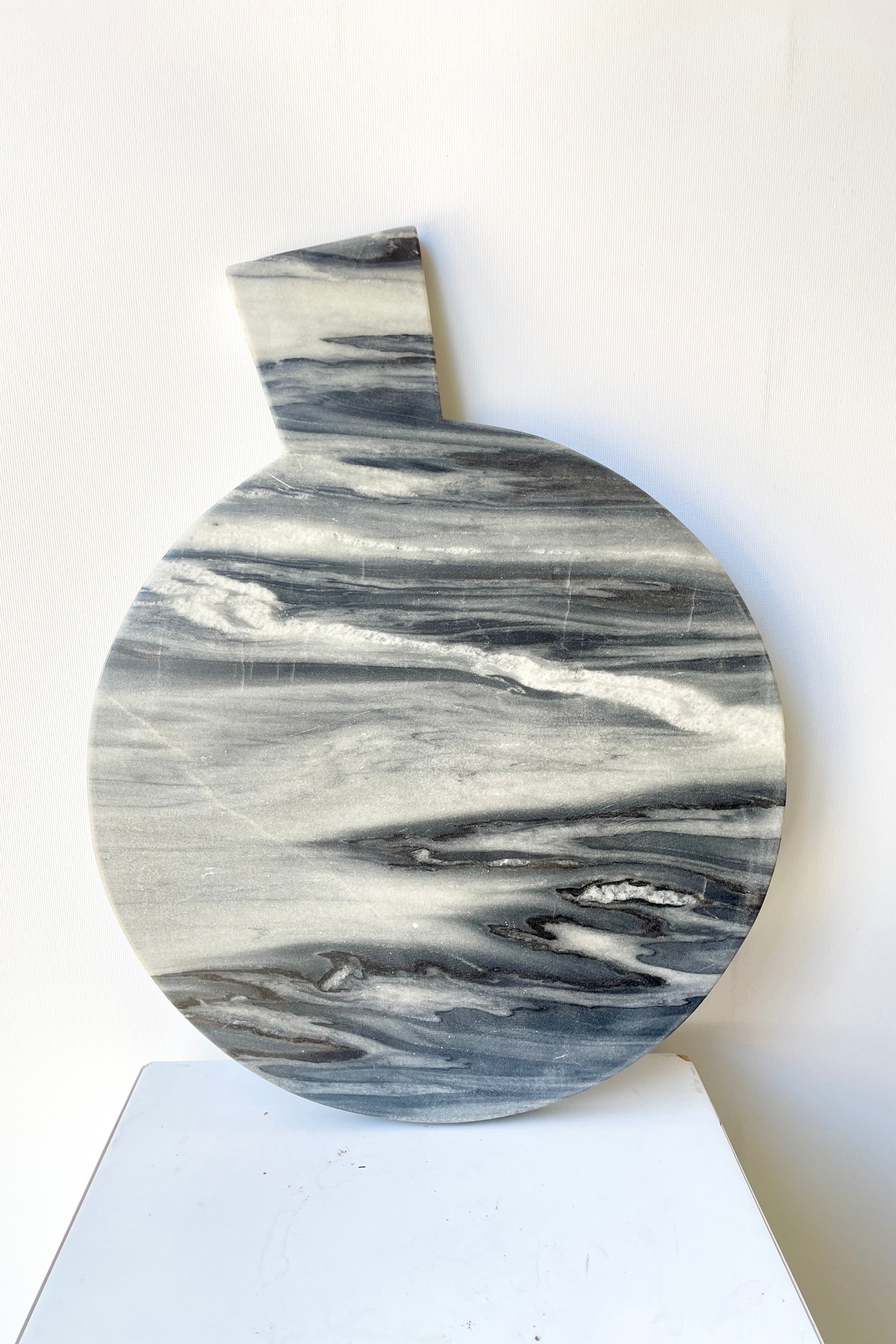 The Black Marble Cheese Board at Sprout Home shown leaning against a white wall.