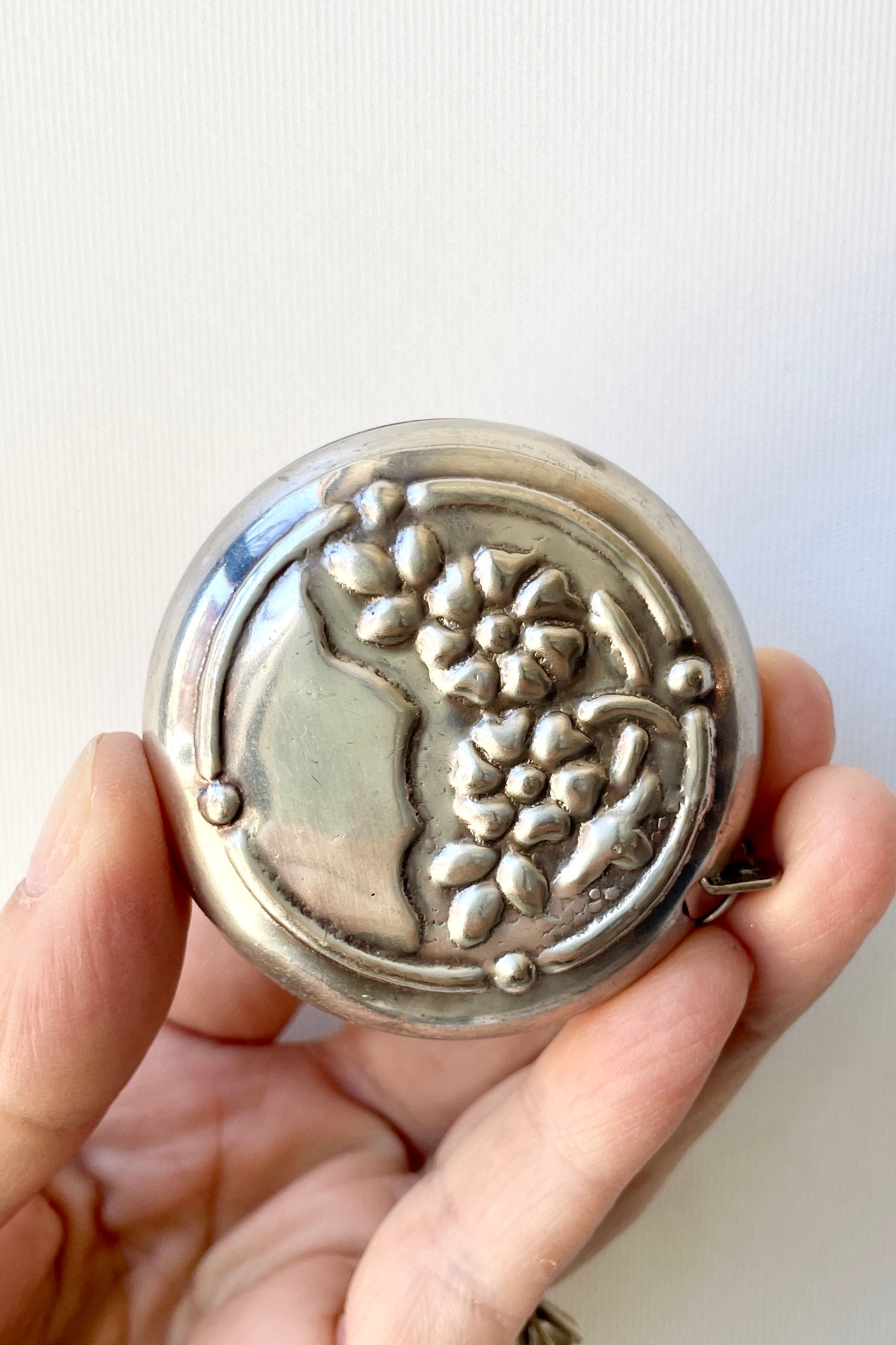 The floral design of the metal flowers measuring tape being held in hand. ©Sprout Home