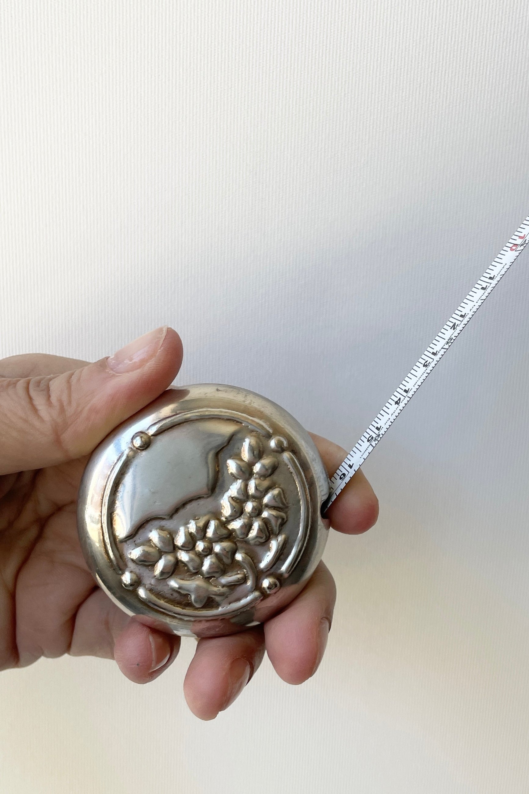 Flowers measuring tape being held in hand with the tape drawn. ©Sprout Home